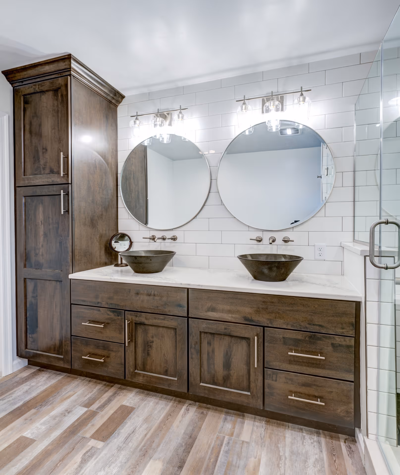 Modern bathroom in Elizabethtown, PA featuring dark wood cabinetry, round mirrors, and unique vessel sinks.