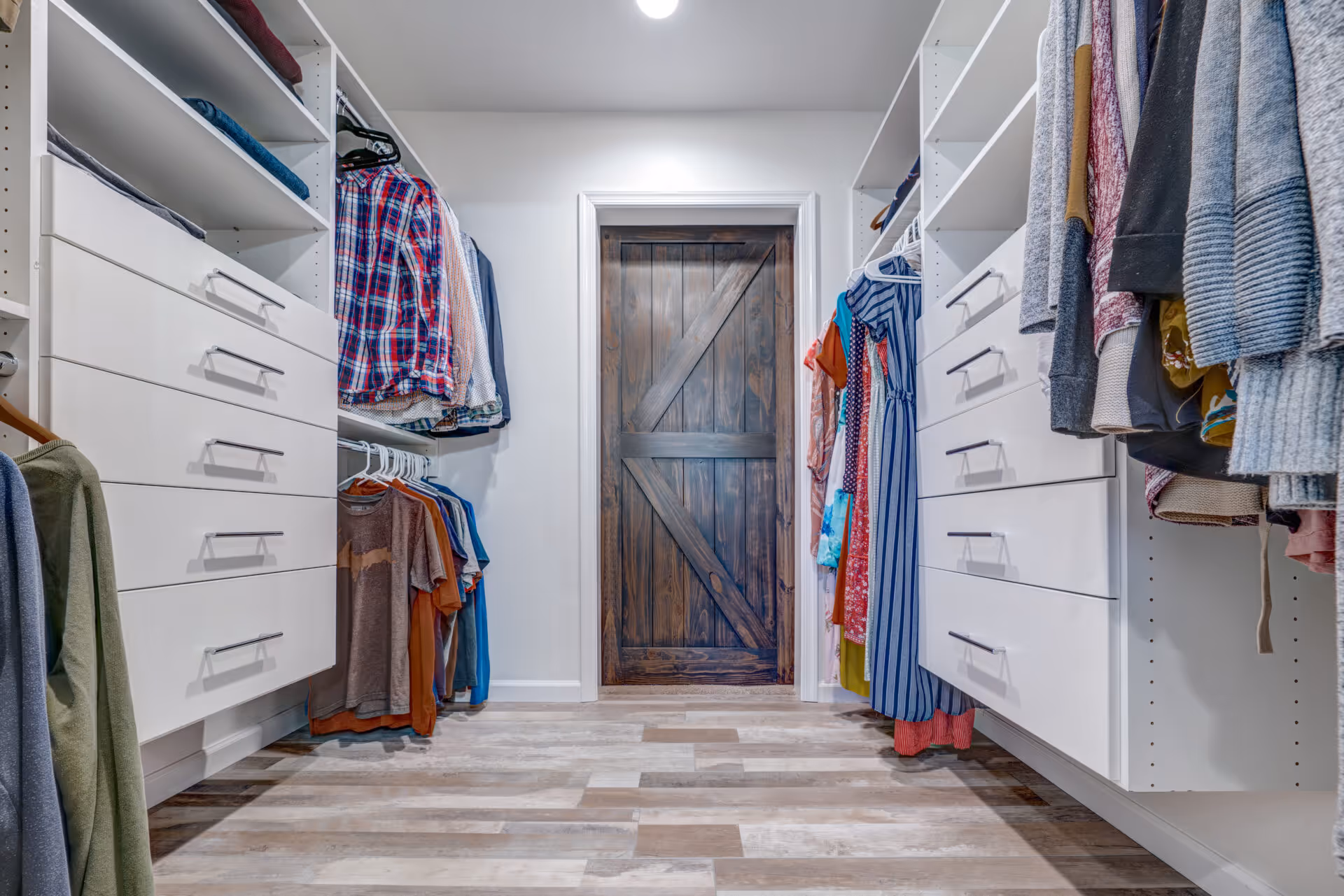 Stylish modern closet in Elizabethtown, PA featuring white cabinets and a rustic wood door.