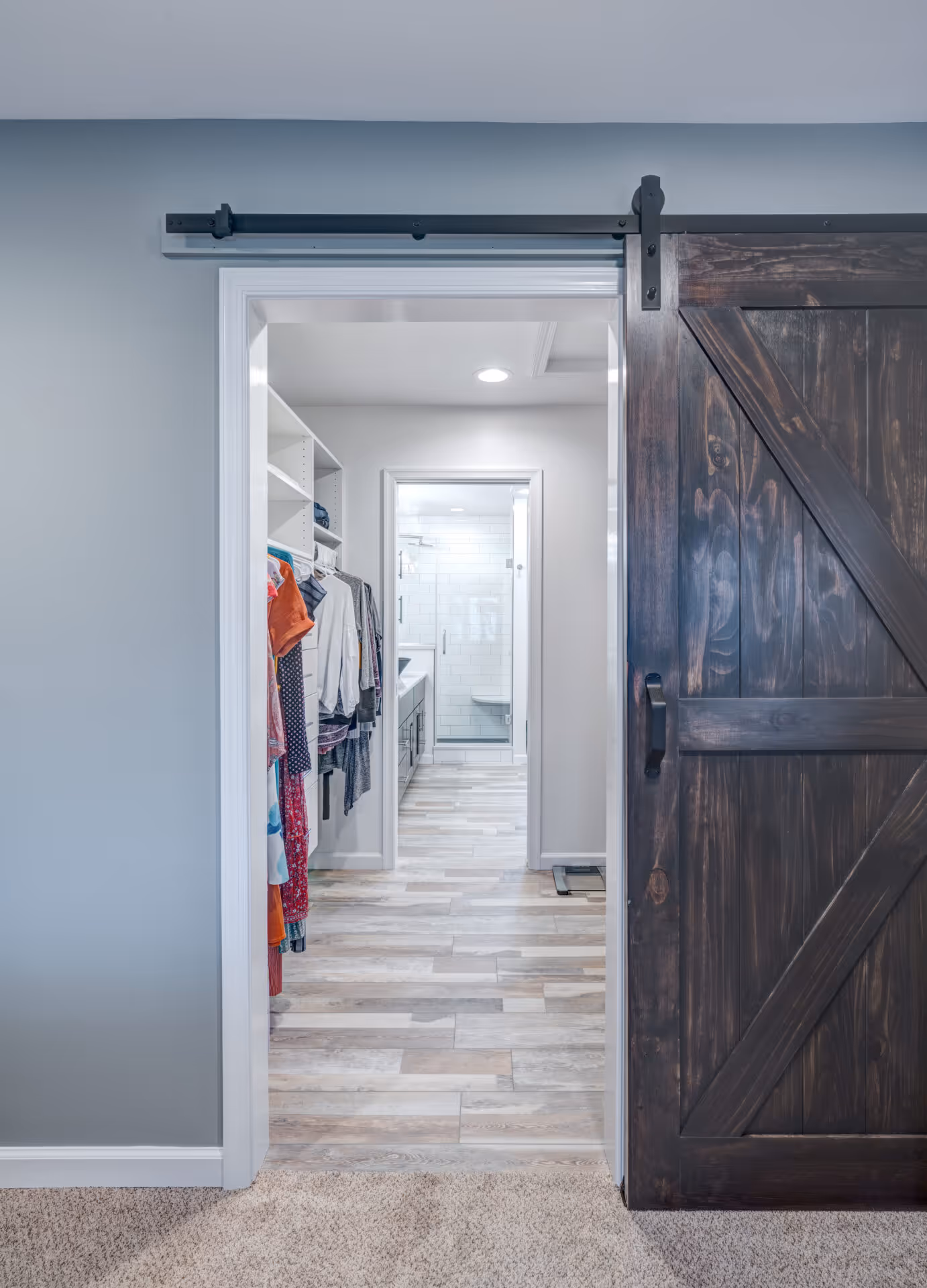 Transitional bathroom with a sliding barn door, stylish closet entrance, and wood tile flooring in Elizabethtown, PA.
