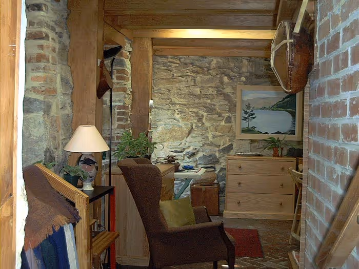 Cozy rustic living room in Boiling Springs, PA featuring stone walls and wooden beams.