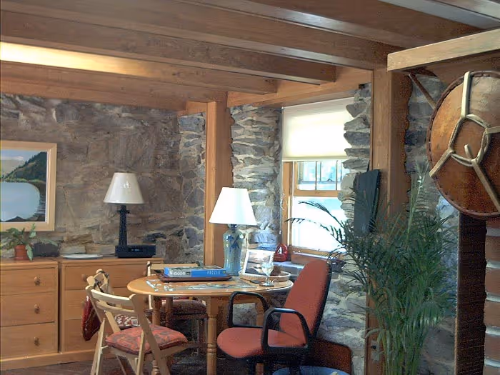 Cozy rustic living room with stone walls, wooden beams, and a circular table in Boiling Springs, PA.