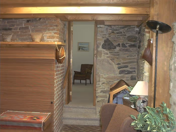 Cozy transitional living room with a brick and stone wall, featuring a lamp and potted plant in Boiling Springs, PA
