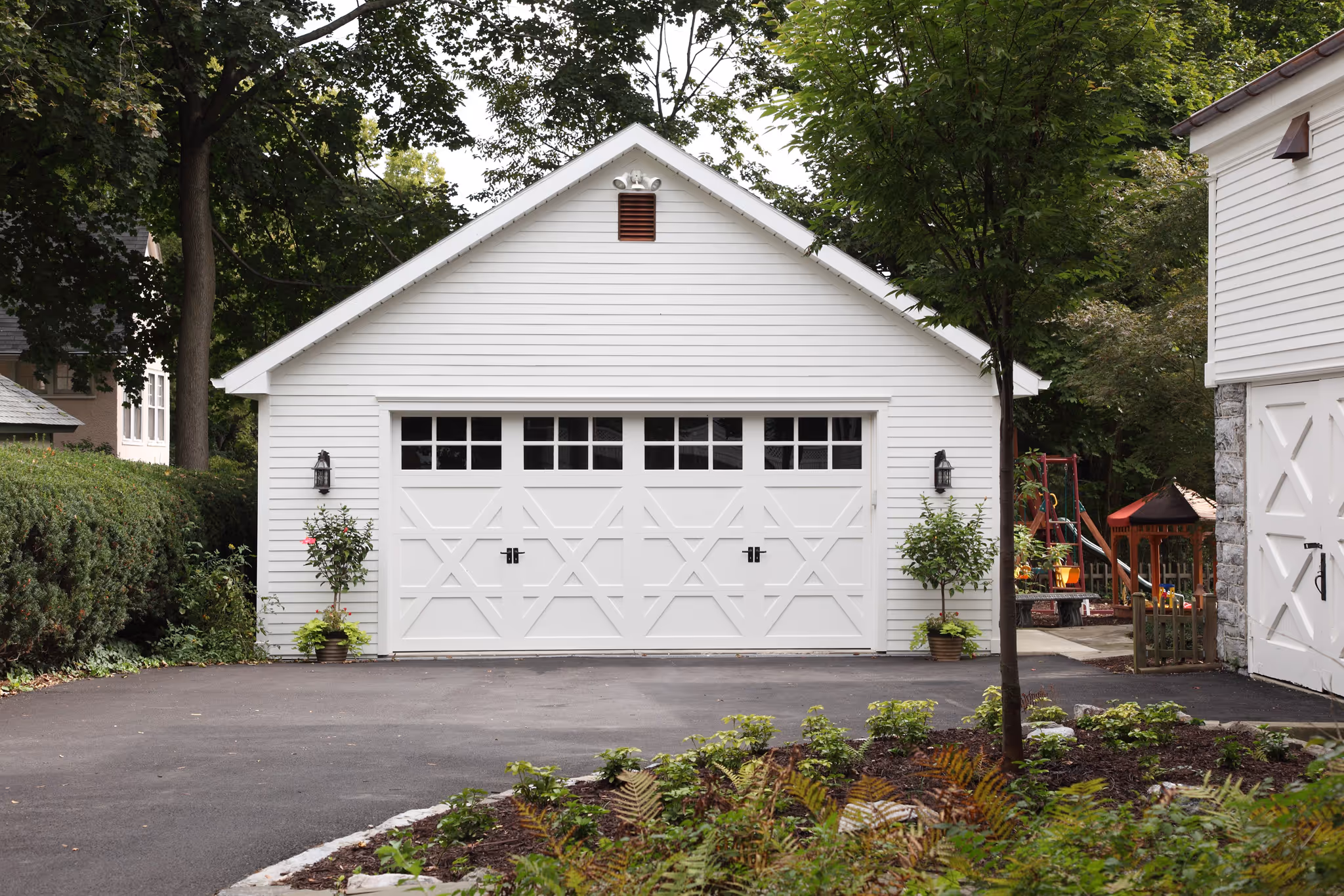 Modern garage with white siding, decorative doors, and landscaping in Harrisburg, PA.