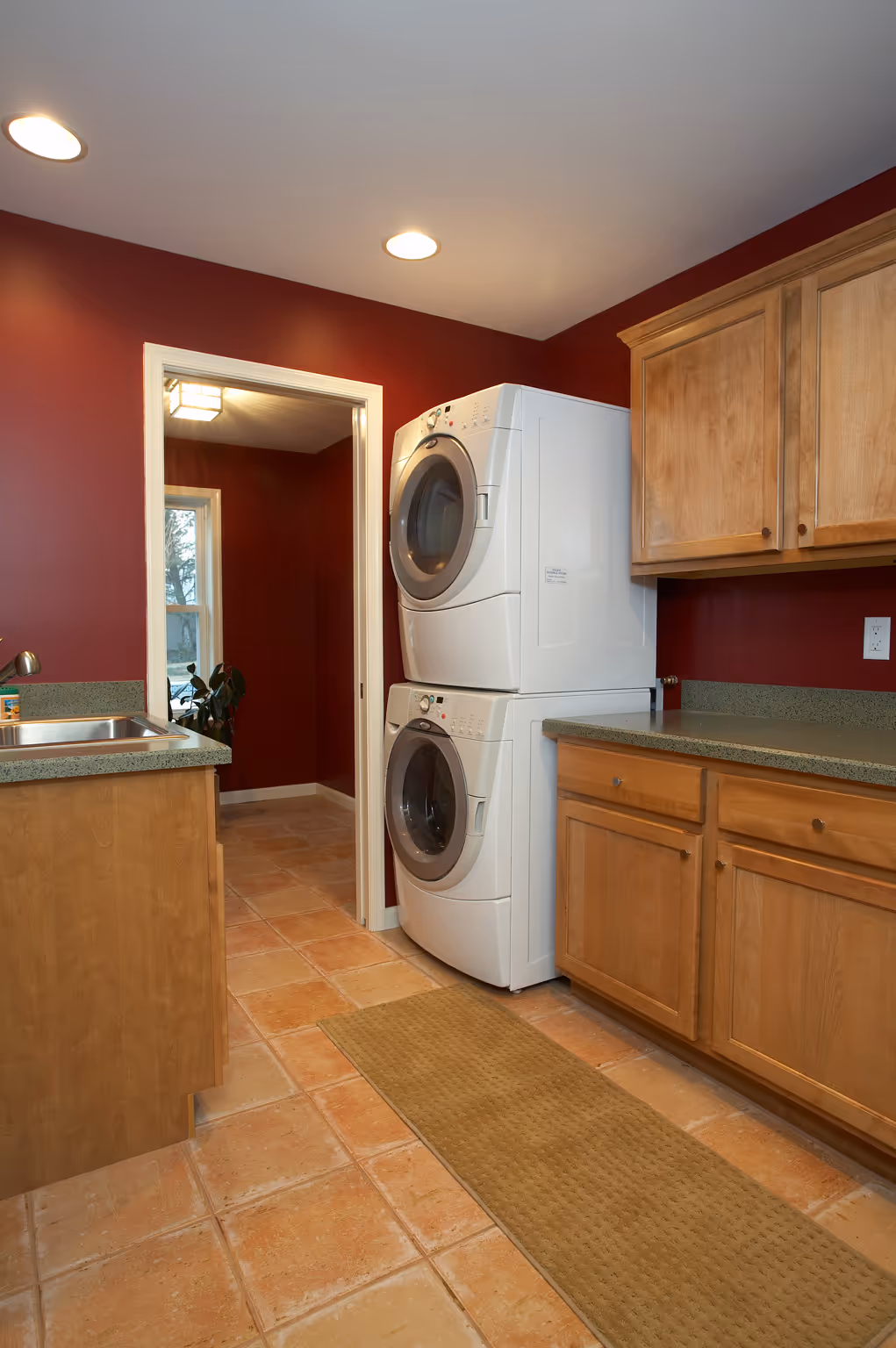 Room with red walls, laundry appliances, and hardwood floor.