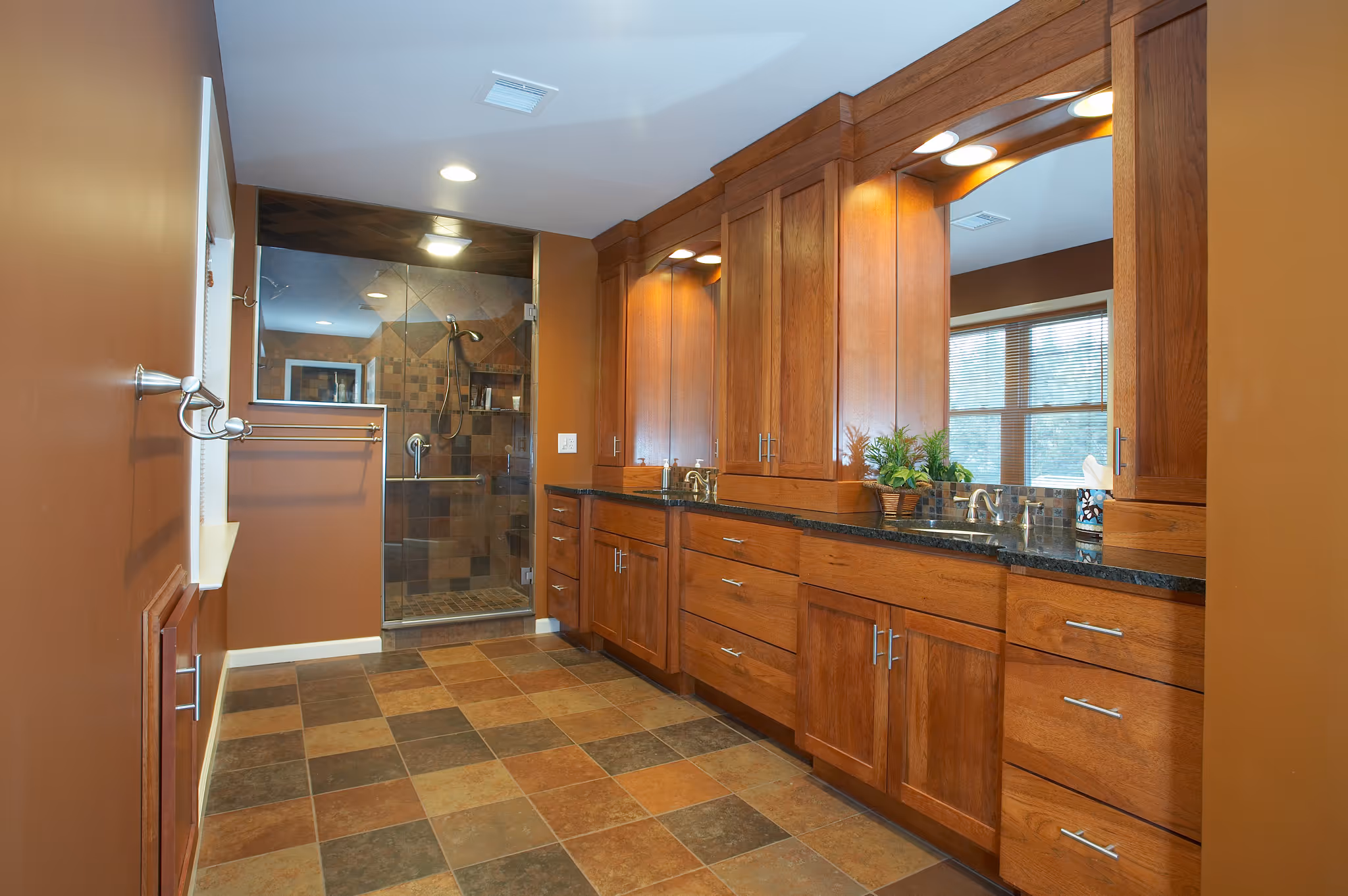 Luxurious primary bathroom featuring wood cabinets, granite countertop, and a tiled walk-in shower in Camp Hill, PA