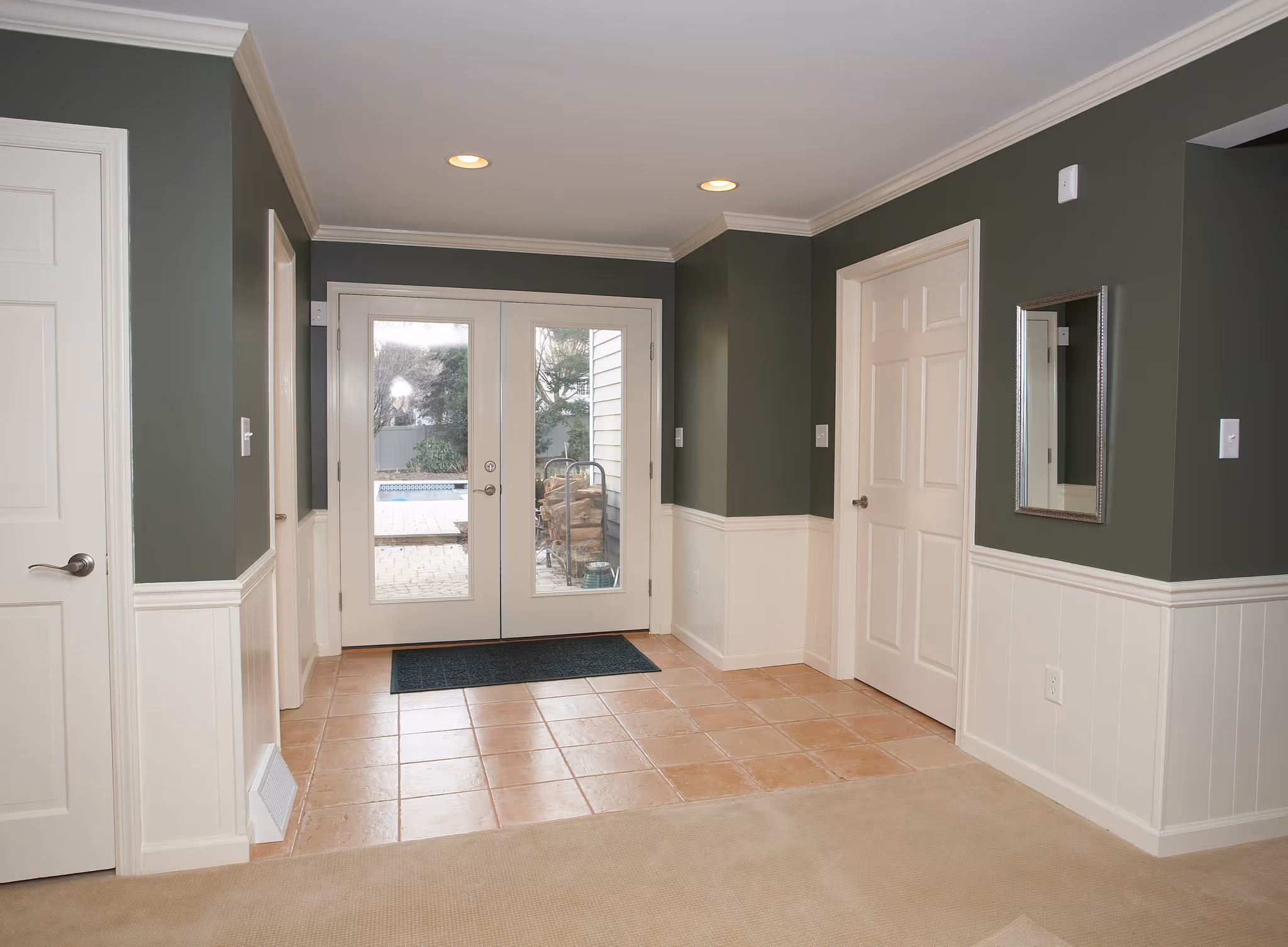 Welcoming entryway featuring green walls and tiled floor in Camp Hill, PA, with large windows leading to an outdoor patio.