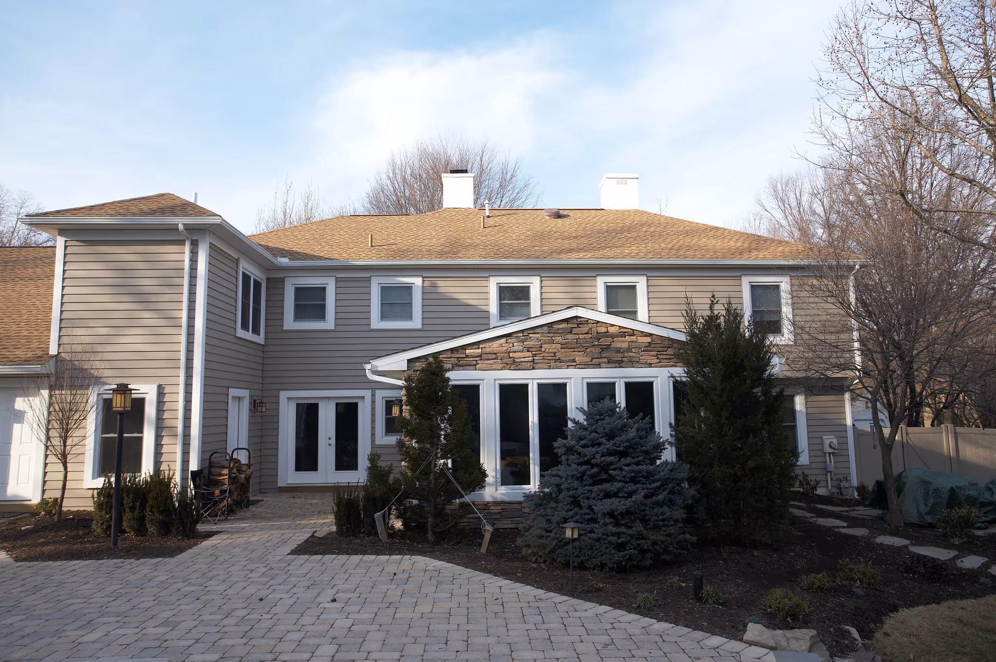 Contemporary exterior view of a home in Camp Hill, PA featuring stone accents, landscaped gardens, and a paved pathway.