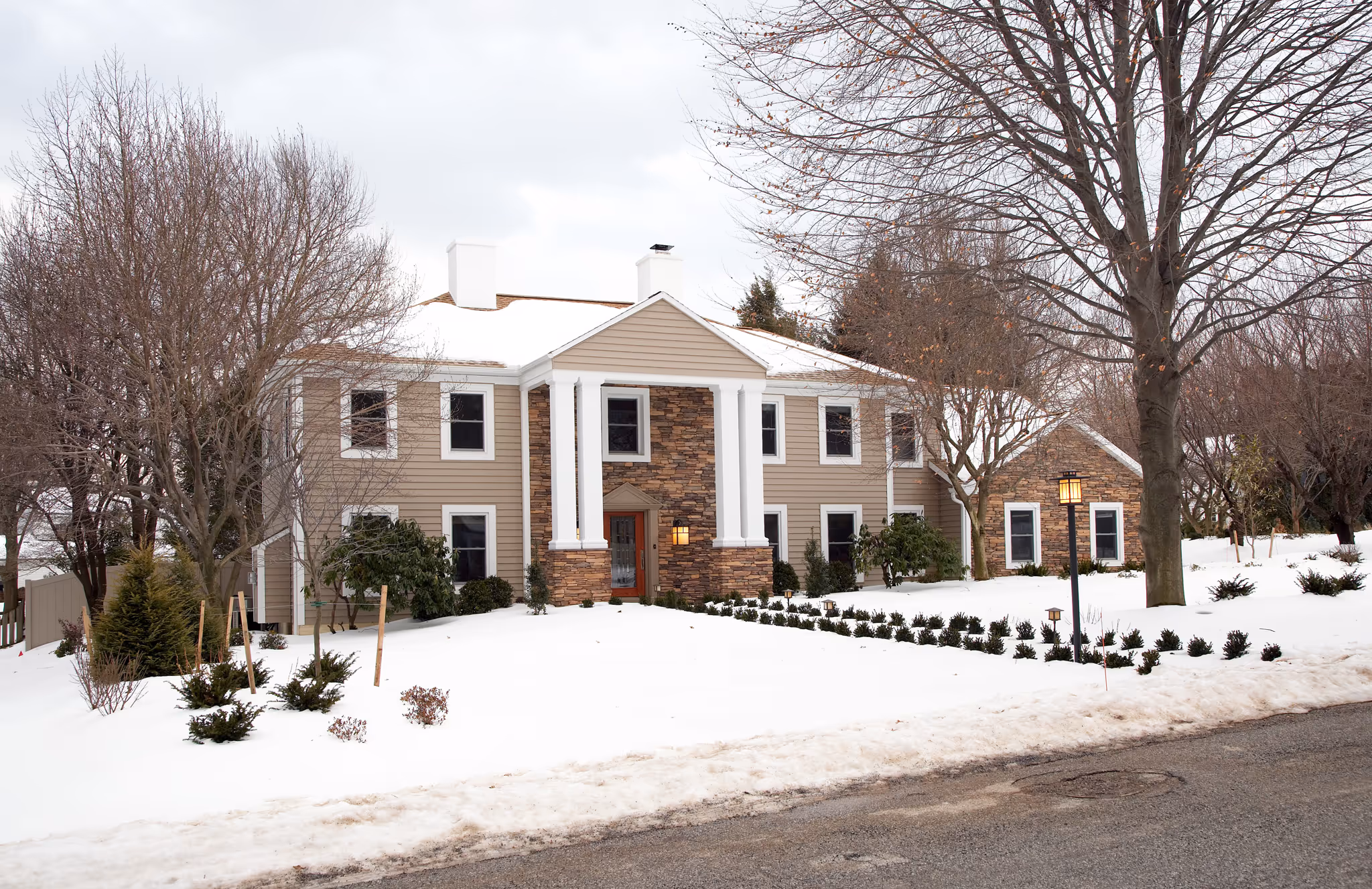 Luxury home exterior featuring a modern design with a stone façade, surrounded by winter snow in Camp Hill, PA.