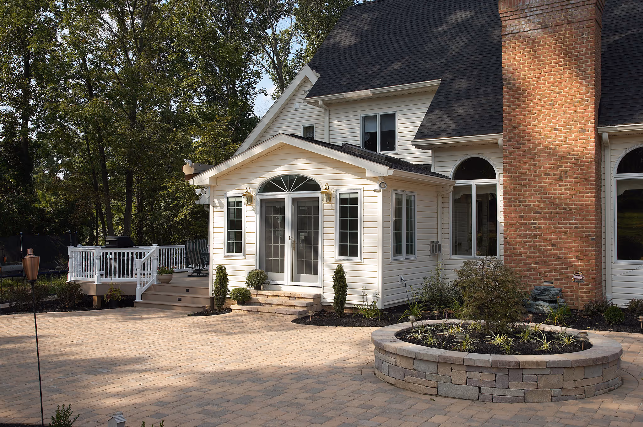 Contemporary exterior of a house with a brick chimney and patio in Middletown, PA, featuring a lovely garden and deck.