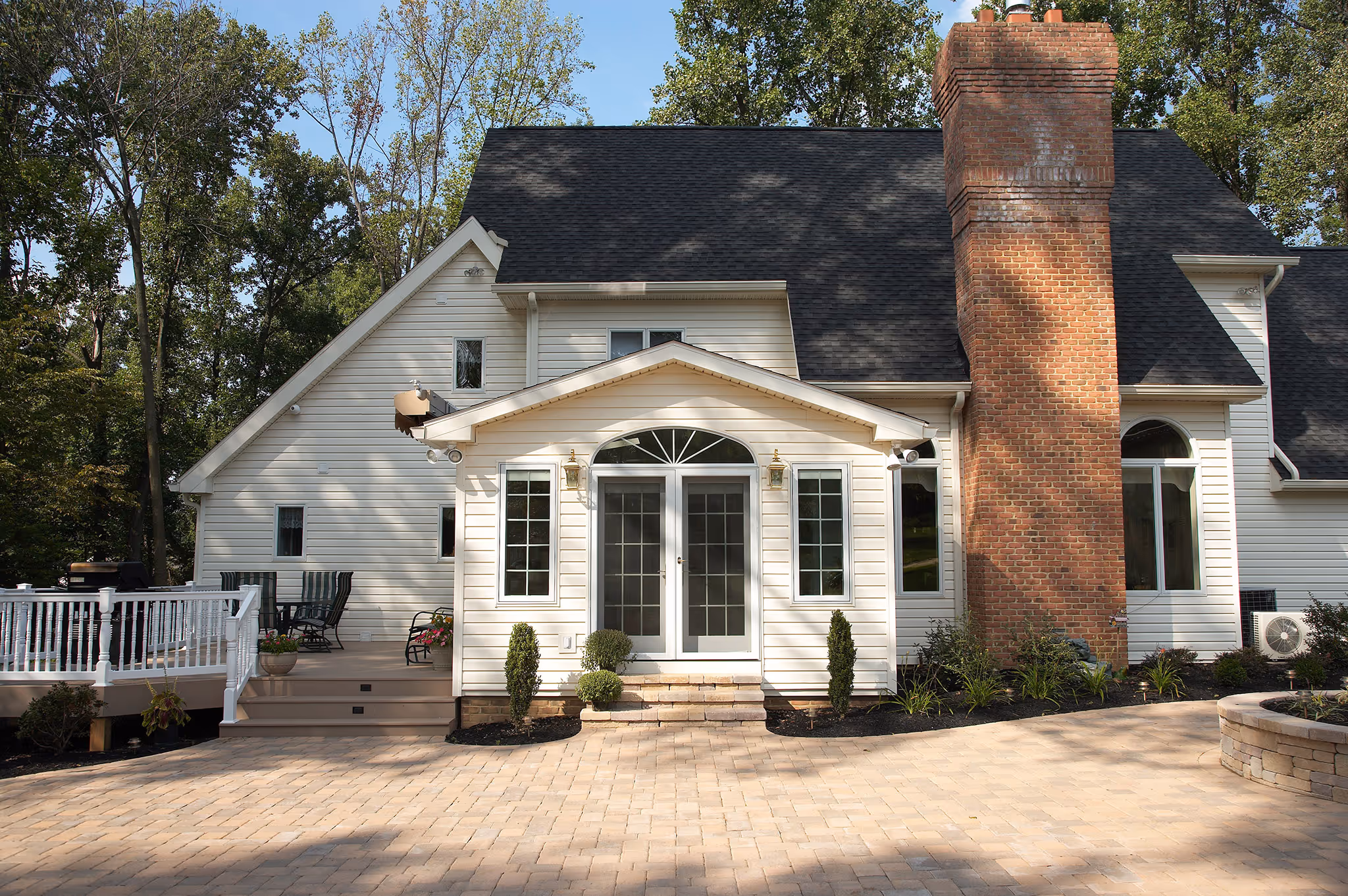 Stylish exterior of a contemporary home in Middletown, PA featuring a brick chimney, double doors, and landscaped garden.