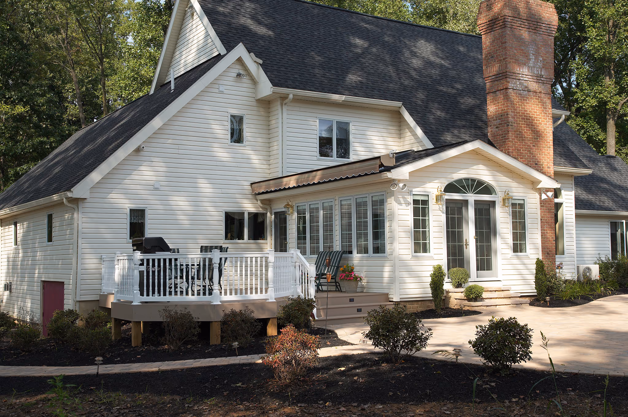 Charming modern exterior of a house in middletown, pa with white siding, a red brick chimney, and a spacious deck.