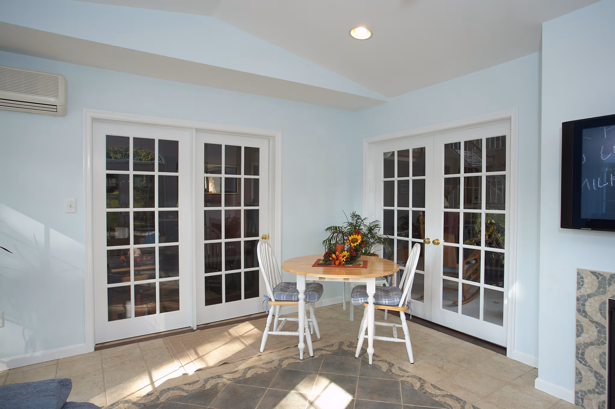 Bright dining nook featuring a round wooden table and two white chairs, surrounded by large glass doors in middletown, pa.