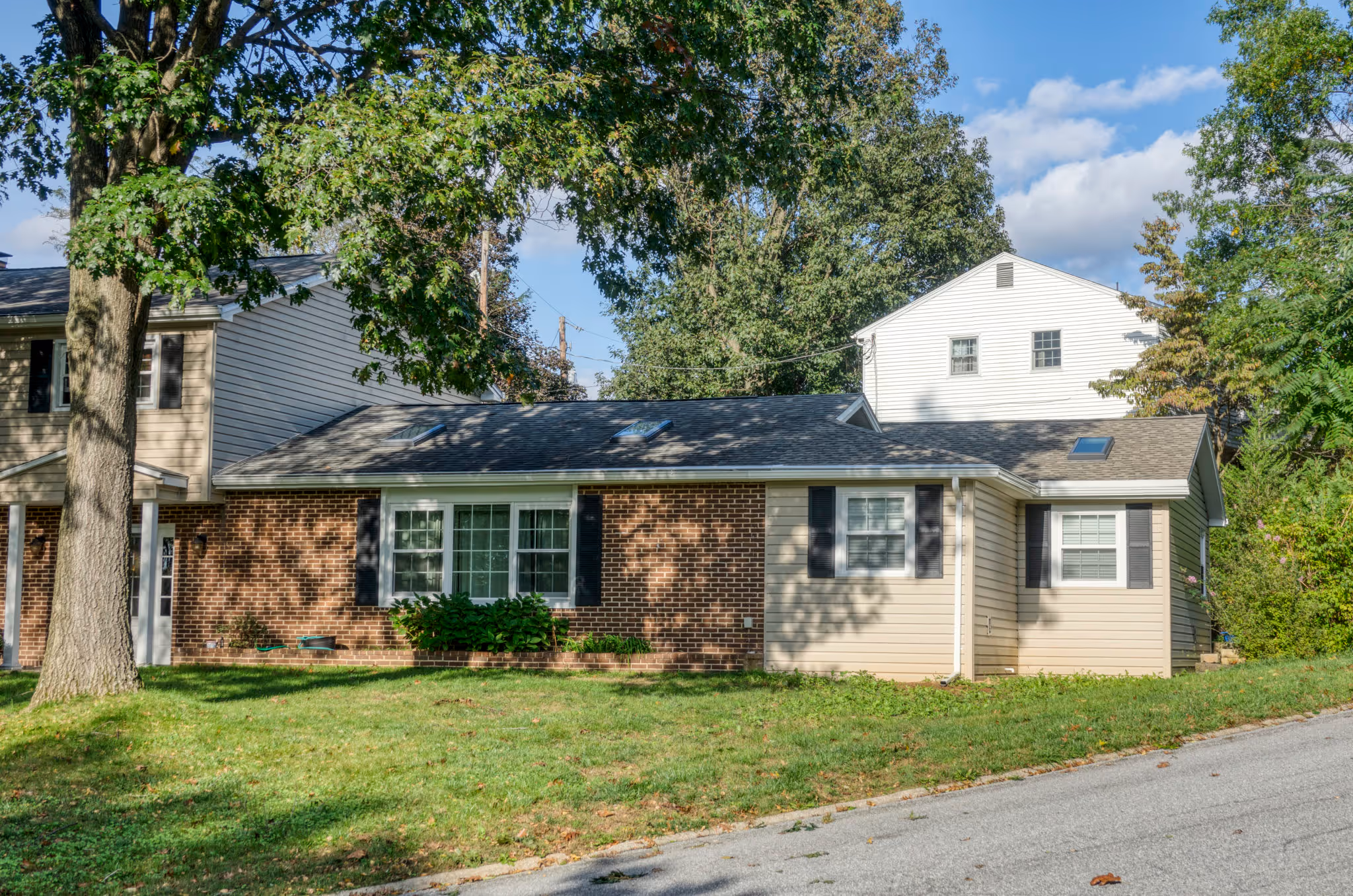 Exterior view of a modern home in Mechanicsburg, PA, featuring a mix of brick and siding, surrounded by green foliage