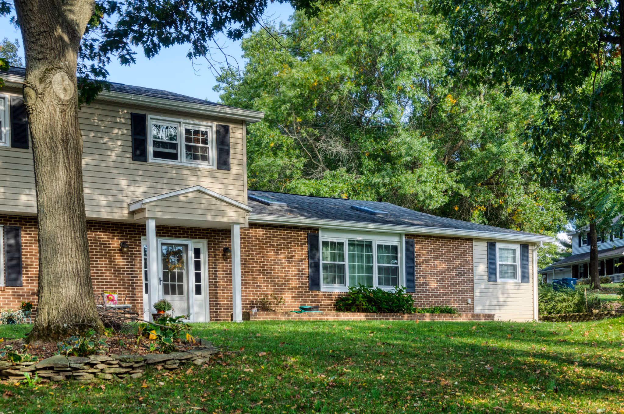 Modern exterior home design with brick and siding in Mechanicsburg, PA, featuring large windows and landscaped yard.