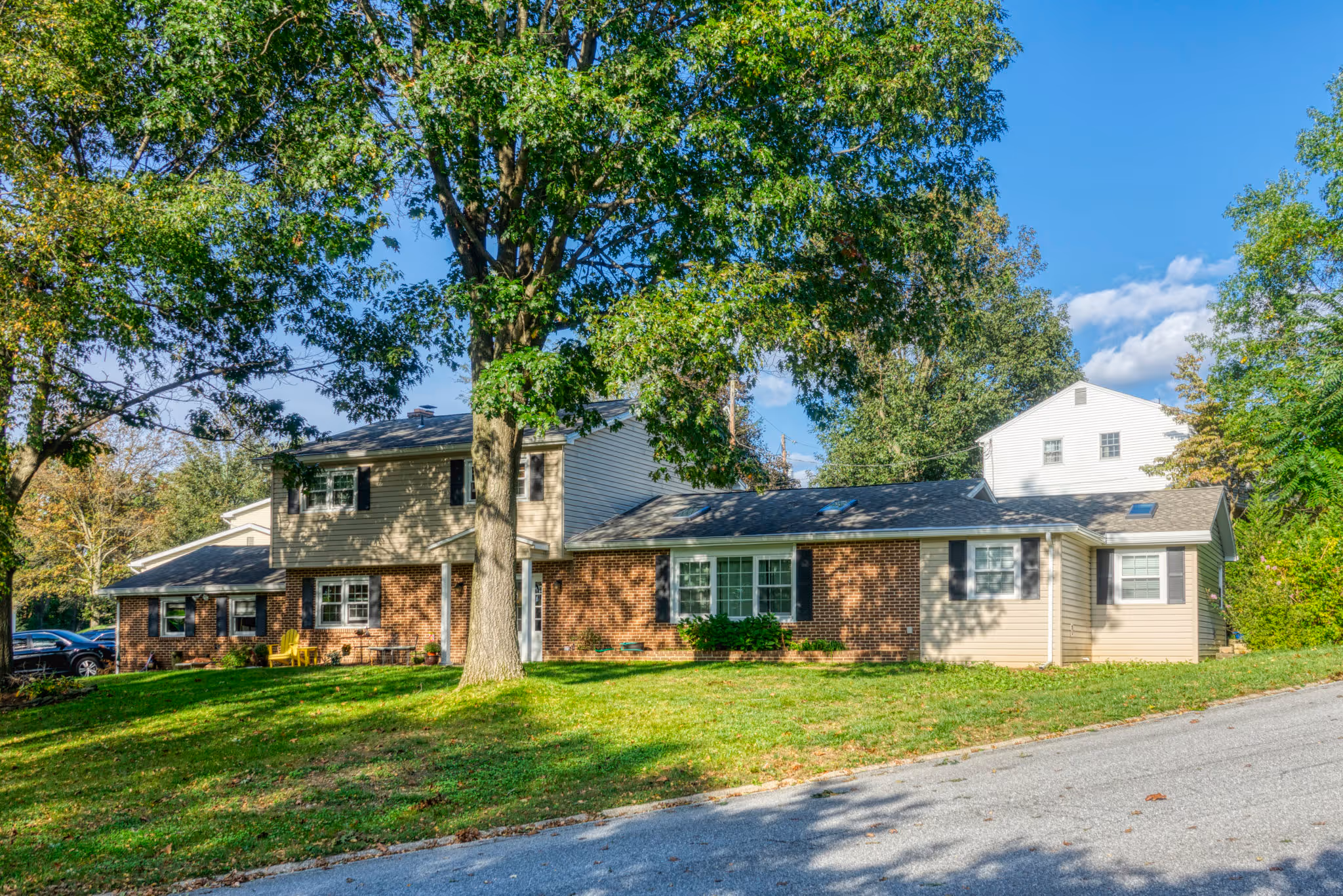 A modern addition to a home in mechanicsburg, pa featuring brick and siding accents, surrounded by greenery.