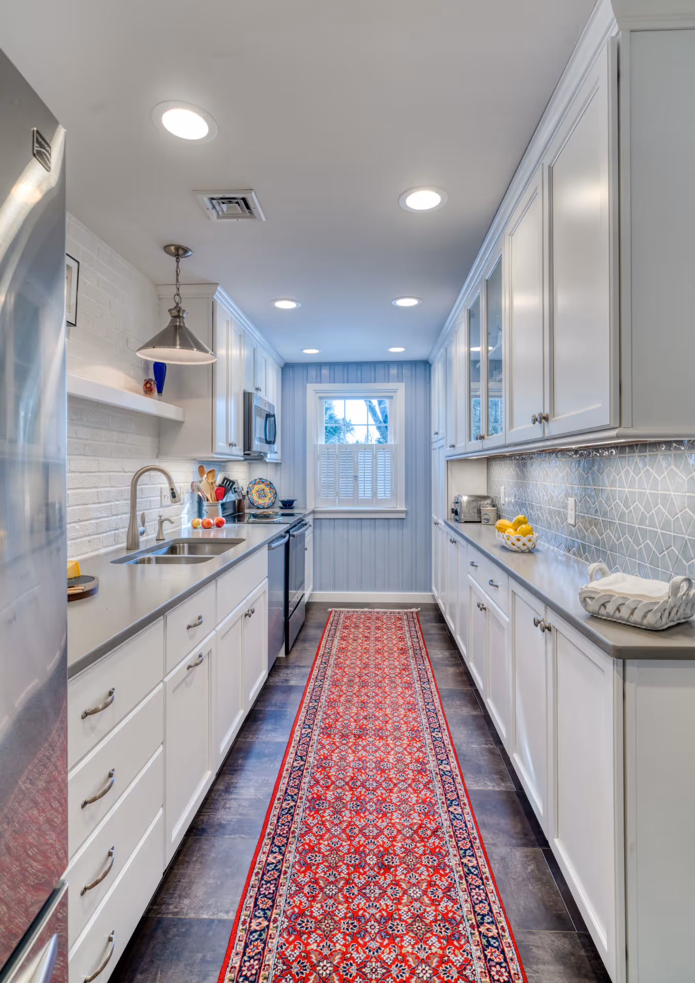 Bright, modern kitchen with white cabinetry and geometric backsplash in Camp Hill, PA, featuring a vibrant red runner rug.
