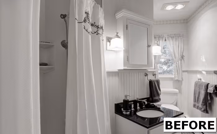Transitional bathroom with white shower curtain, black granite countertop, and wood cabinetry in camp hill, pa