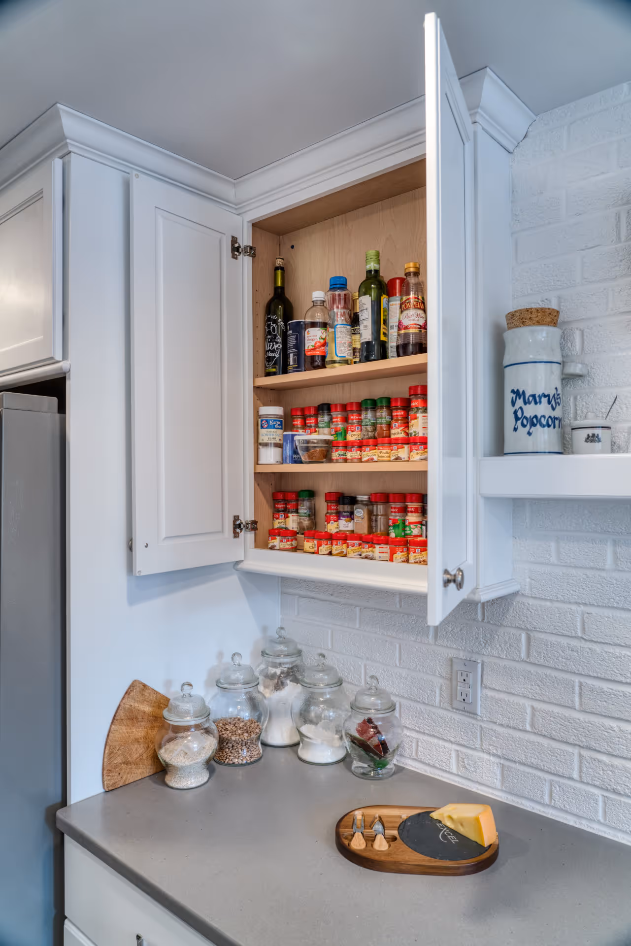 Bright modern kitchen with white cabinetry and spice jars, located in Camp Hill, PA.