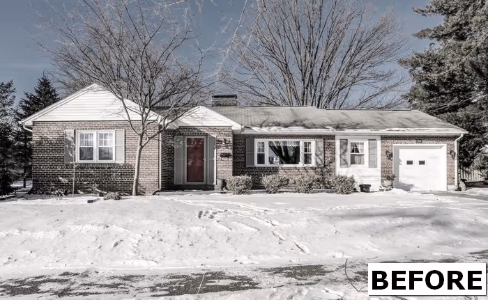 Charming traditional brick exterior home in Camp Hill, PA, surrounded by snow and mature trees.