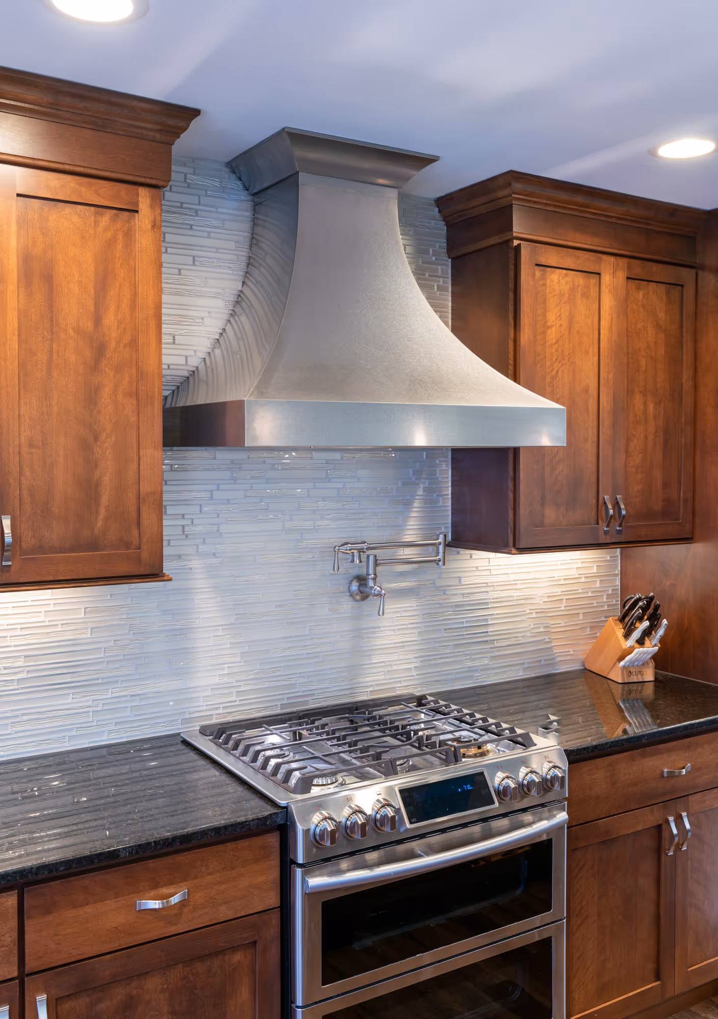Modern kitchen in Hershey, PA featuring dark wood cabinetry, stainless steel range, and gray tile backsplash.