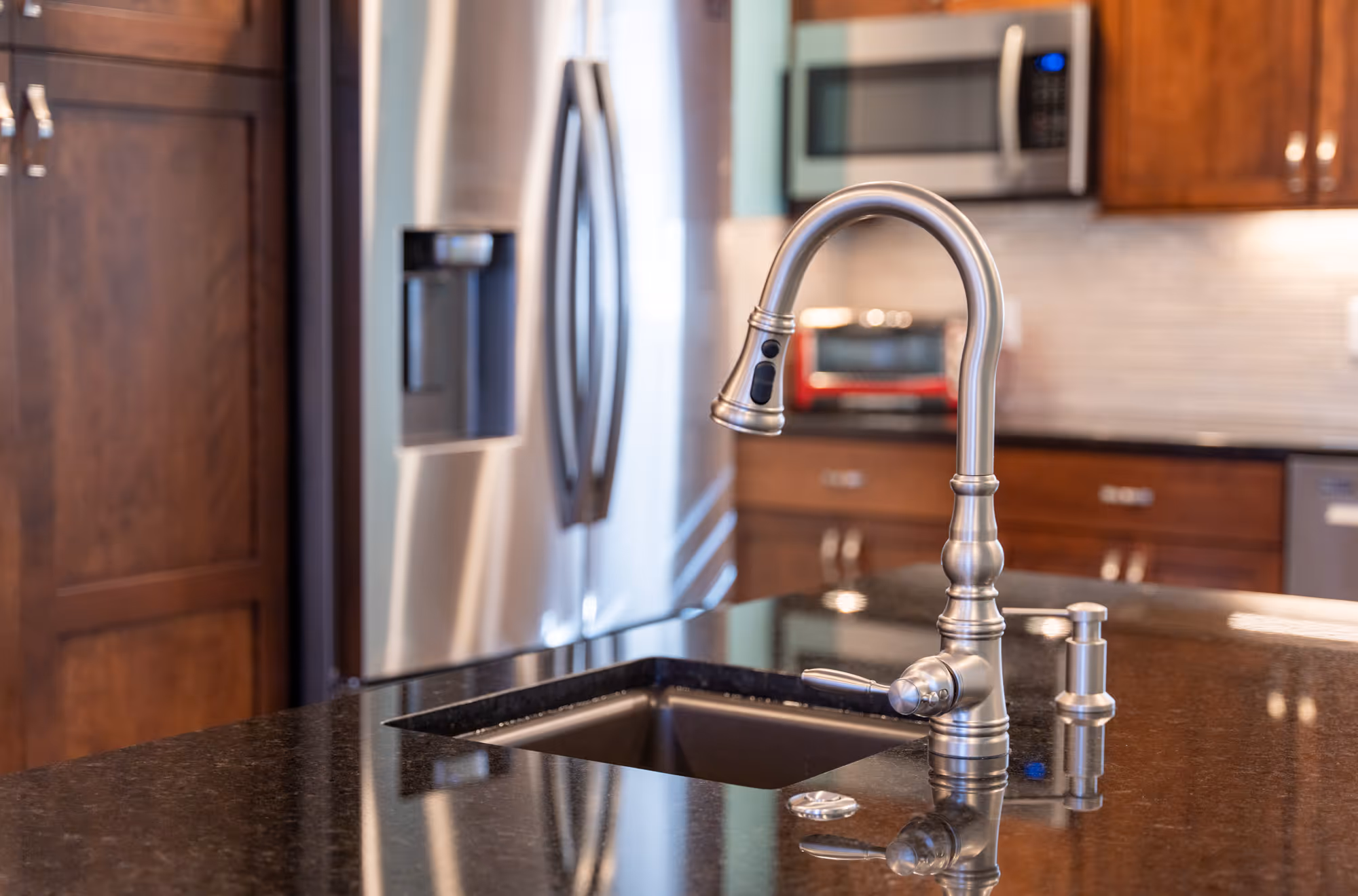 Modern kitchen sink with stainless steel faucet and dark granite countertop in Hershey, PA.