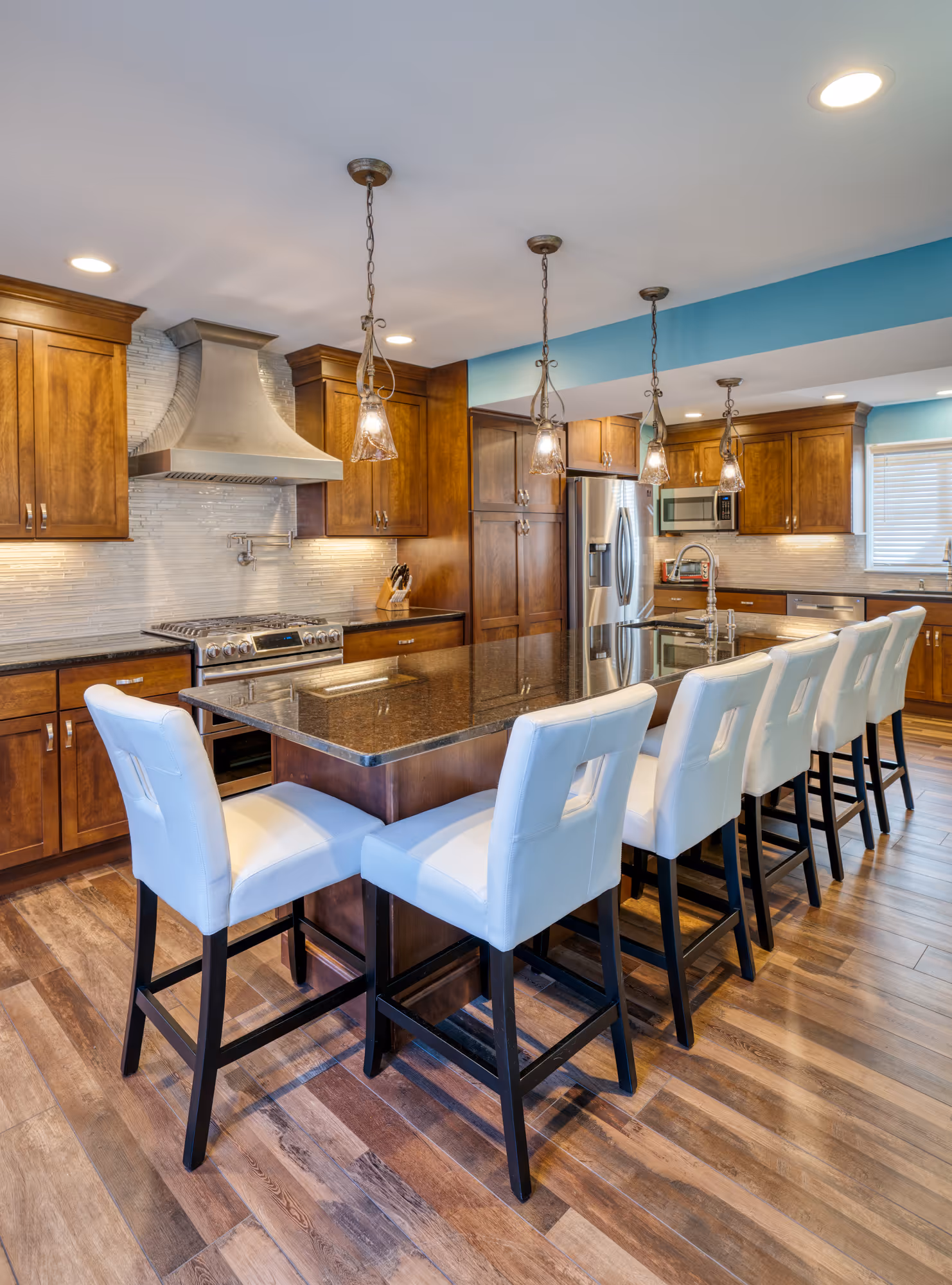 Modern kitchen in Hershey, PA featuring granite countertops, dark wood cabinetry, and stylish pendant lighting