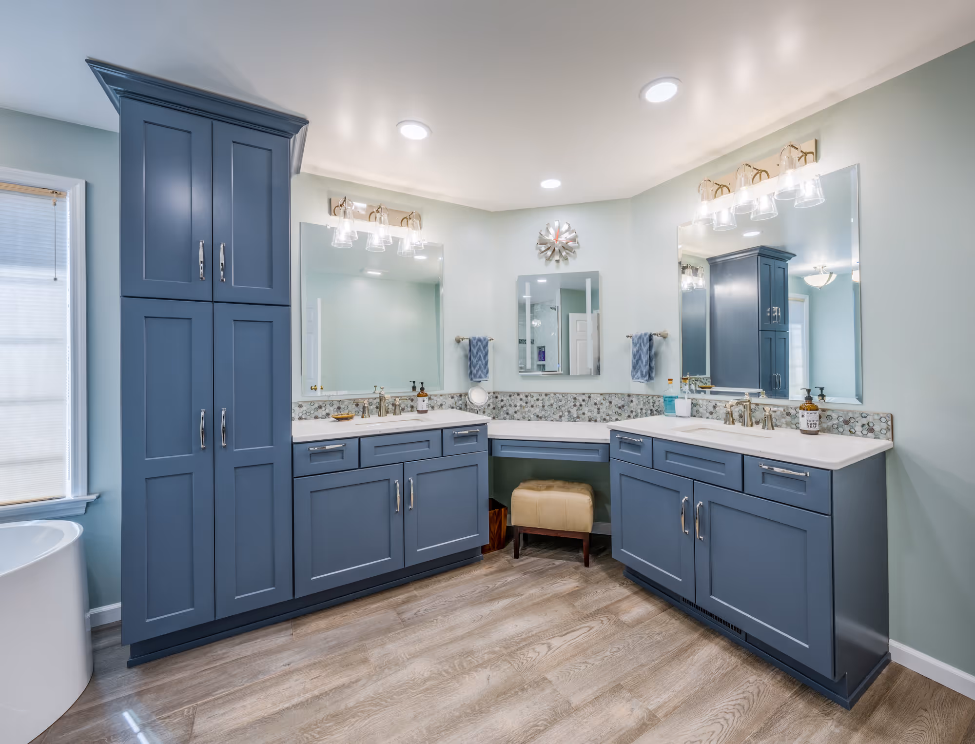Modern bathroom vanity with blue cabinets and double sink in Enola, PA, featuring unique backsplash and wooden flooring.