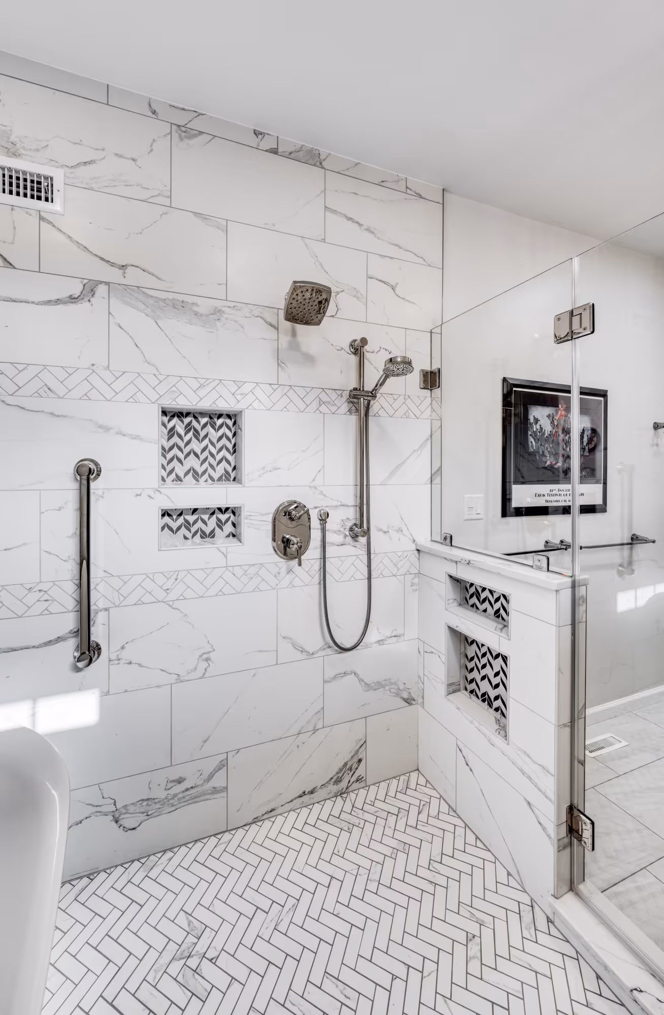 Modern bathroom remodel in Camp Hill, PA featuring a walk-in shower with white marble tile and herringbone patterned floor.