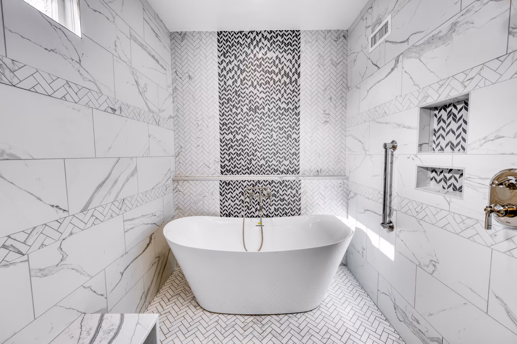 Modern bathroom in Camp Hill, PA featuring a freestanding tub, herringbone tile, and elegant marble accents.