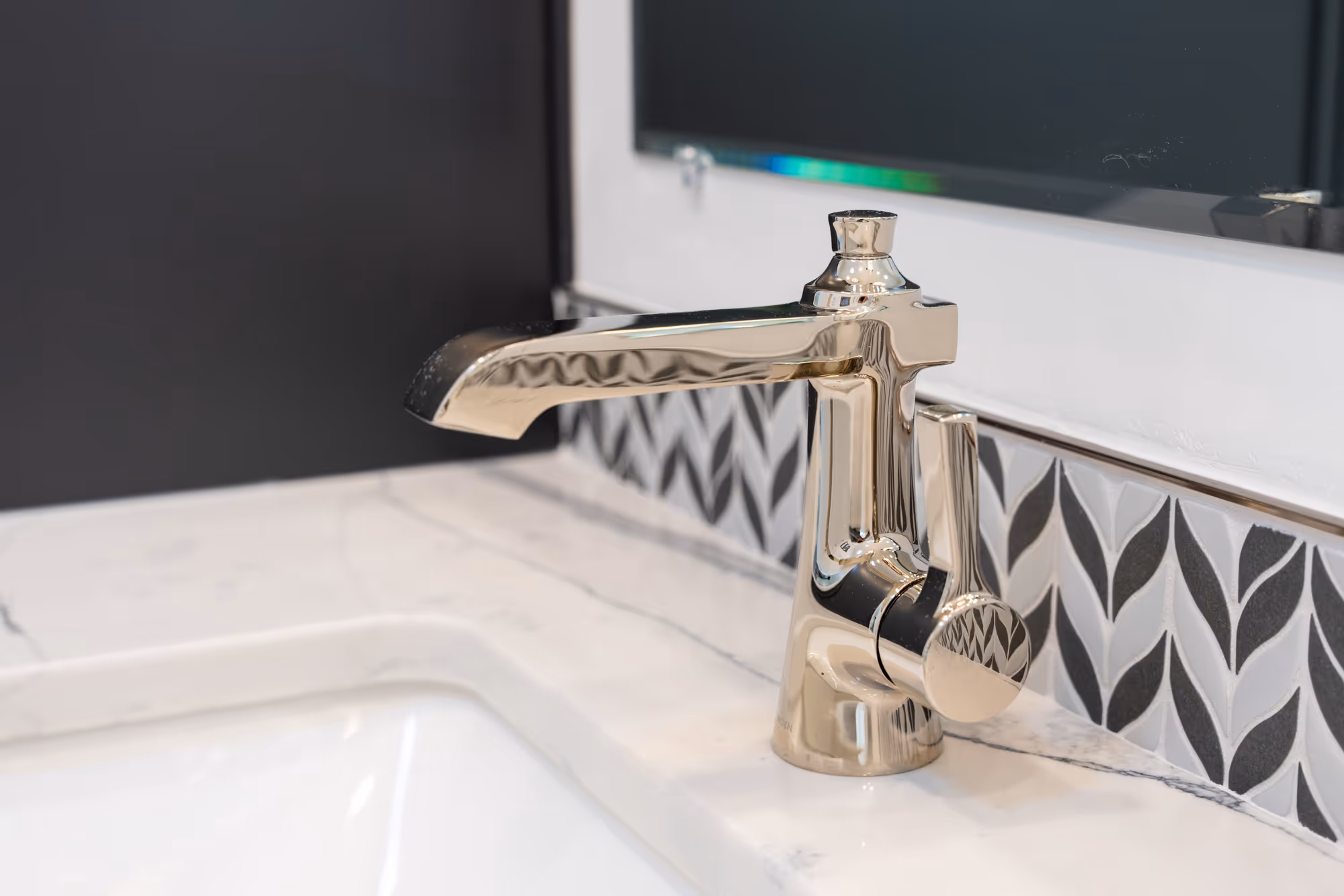 Modern bathroom sink faucet with polished chrome finish and patterned backsplash in Camp Hill, PA.