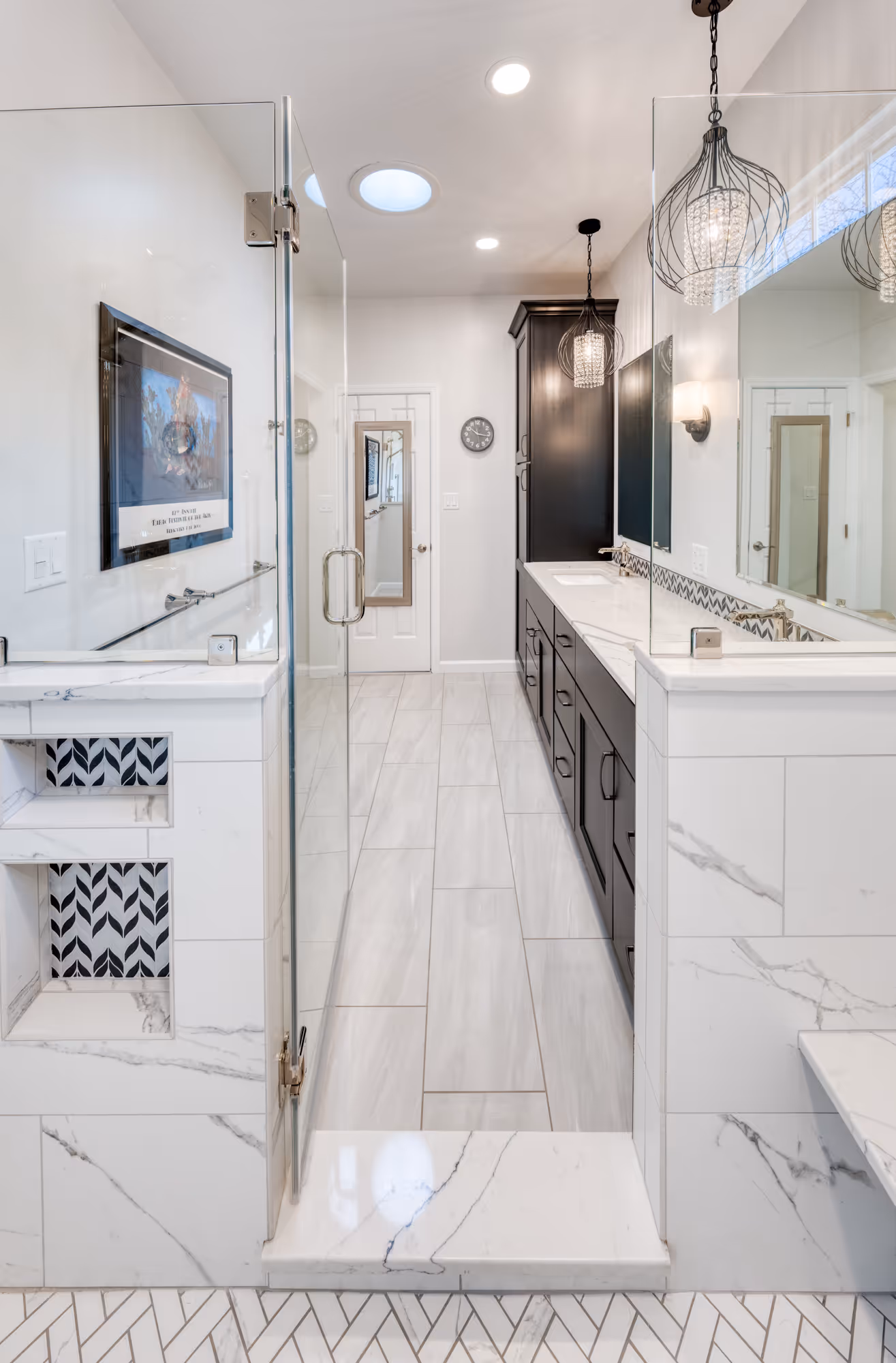 Modern bathroom remodel in Camp Hill, PA featuring a glass shower, black cabinetry, and stylish herringbone tile flooring.