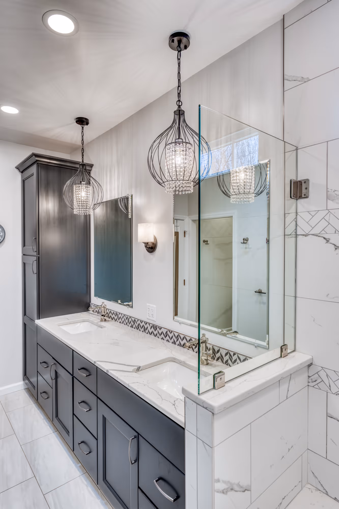 Modern bathroom in Camp Hill, PA featuring dual vanities, marble countertops, and unique glass light fixtures.