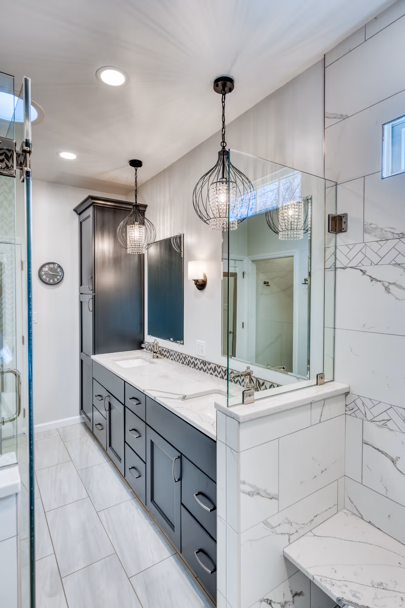 Modern bathroom in Camp Hill, PA featuring dark cabinetry, marble countertops, and elegant pendant lighting.