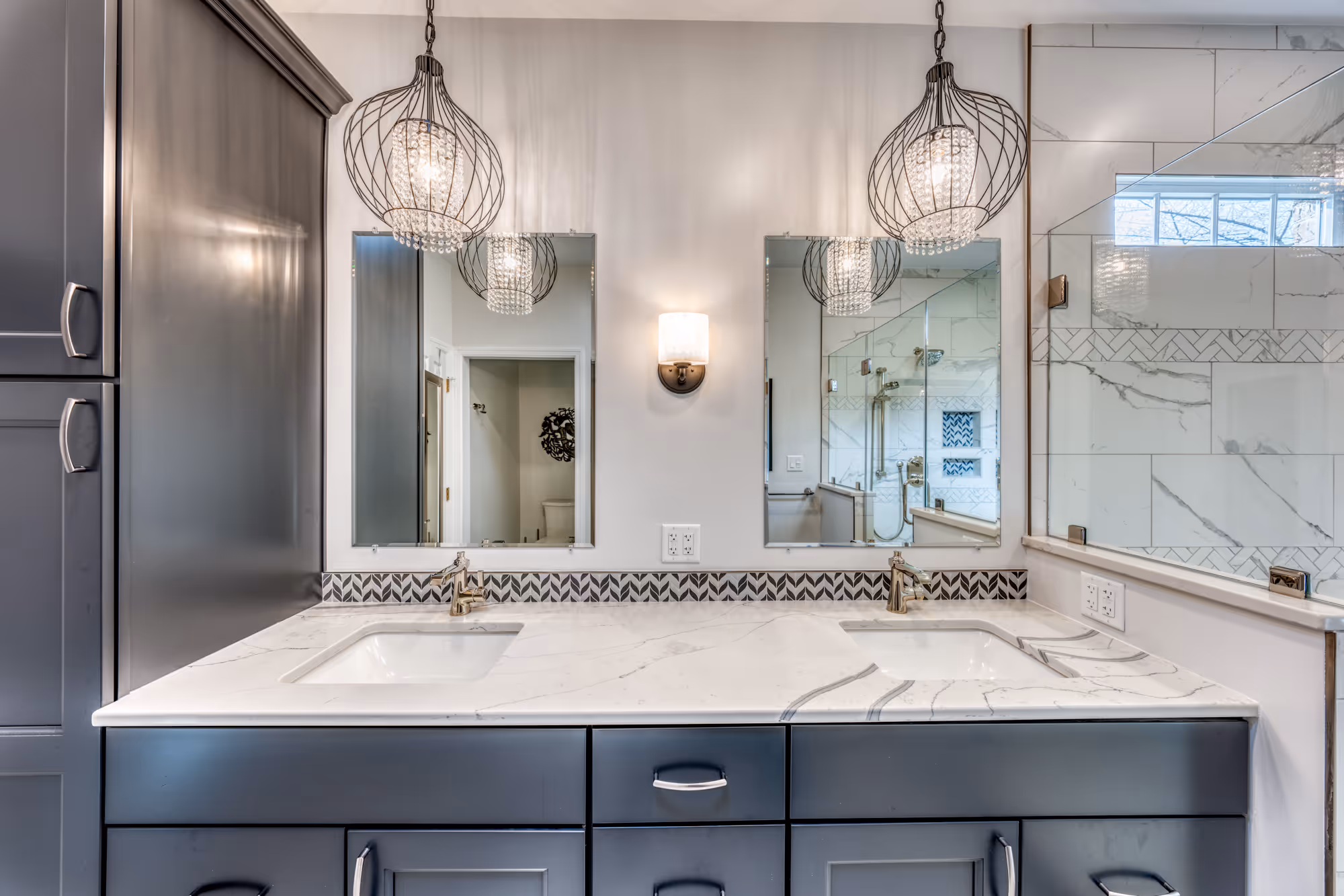 Modern bathroom in Camp Hill, PA featuring black cabinets, marble countertop, and decorative pendant lights.