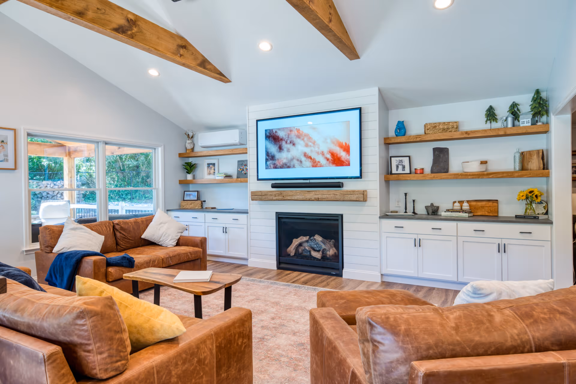 Modern living room in Dillsburg, PA featuring leather sofas, wooden shelves, and a cozy fireplace.