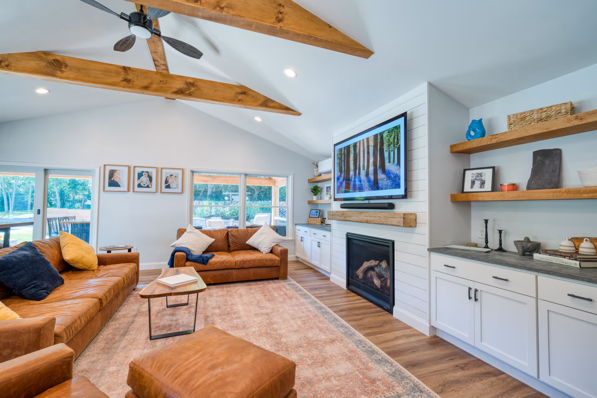 Spacious modern living room with a blend of leather sofas, wooden beams, a fireplace, and large windows in Dillsburg, PA.