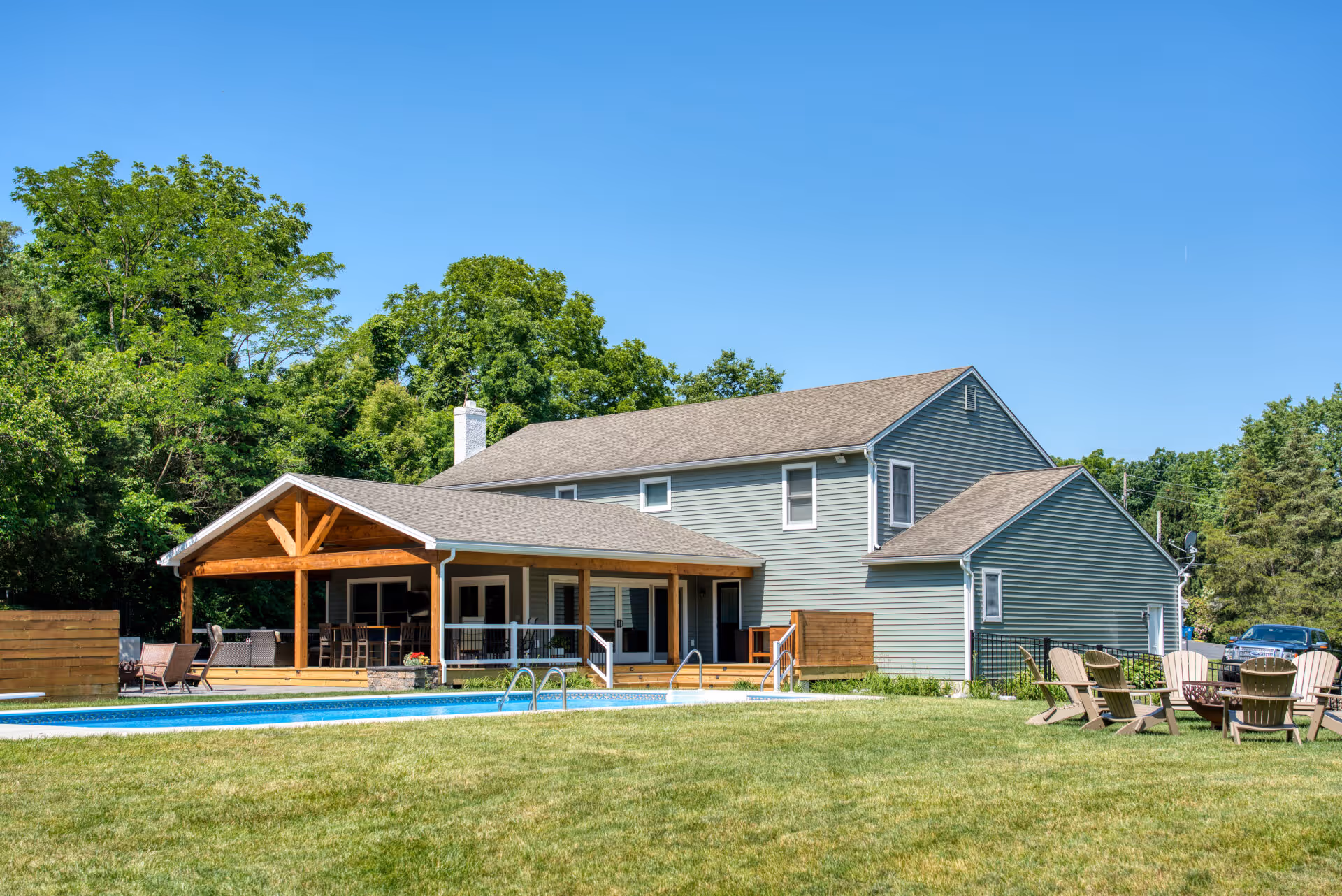 A modern exterior view of a Dillsburg, PA home featuring a spacious patio, swimming pool, and lush greenery.