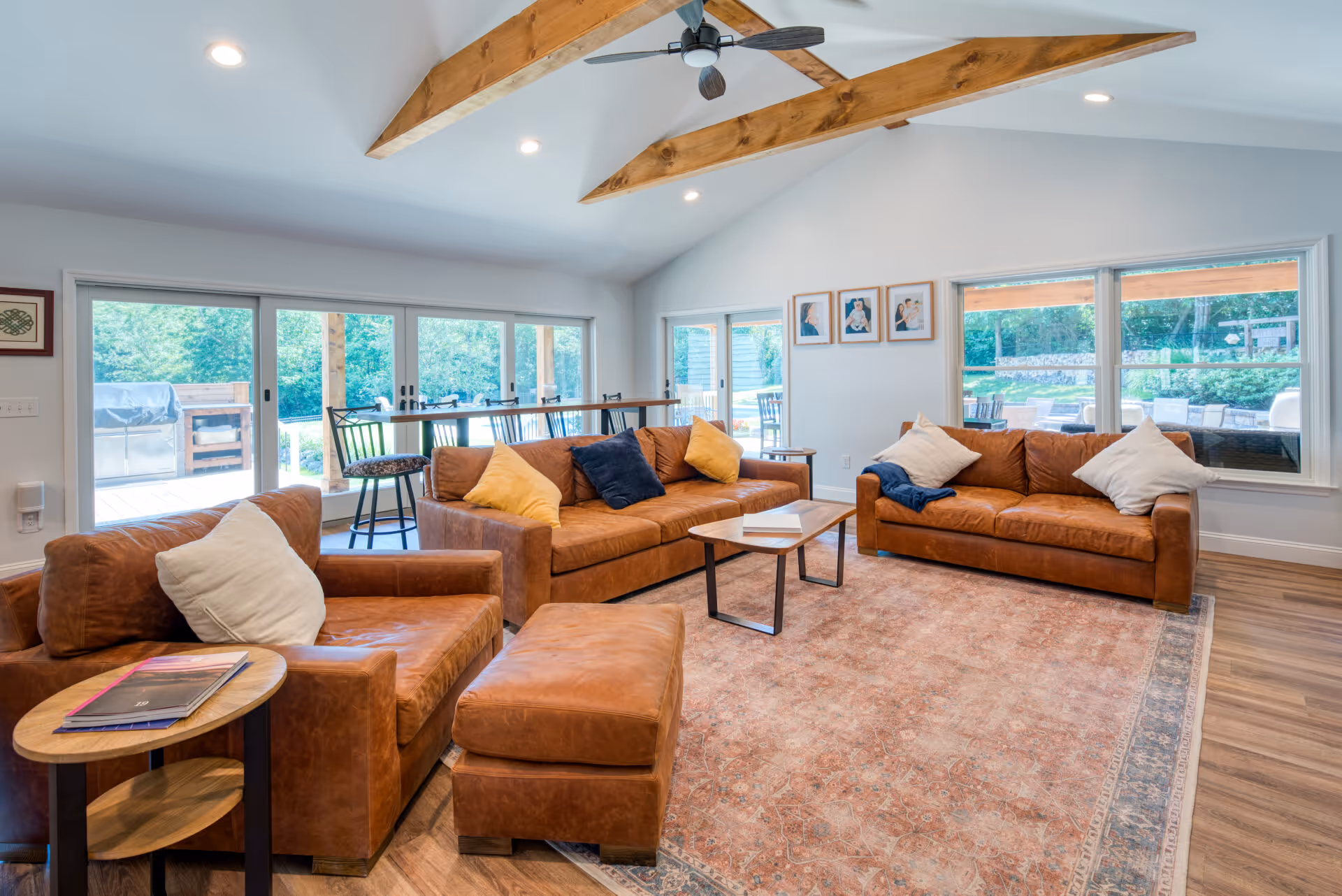 Contemporary living room with leather sofas and wooden beams in Dillsburg, PA, showcasing large windows and a cozy atmosphere.