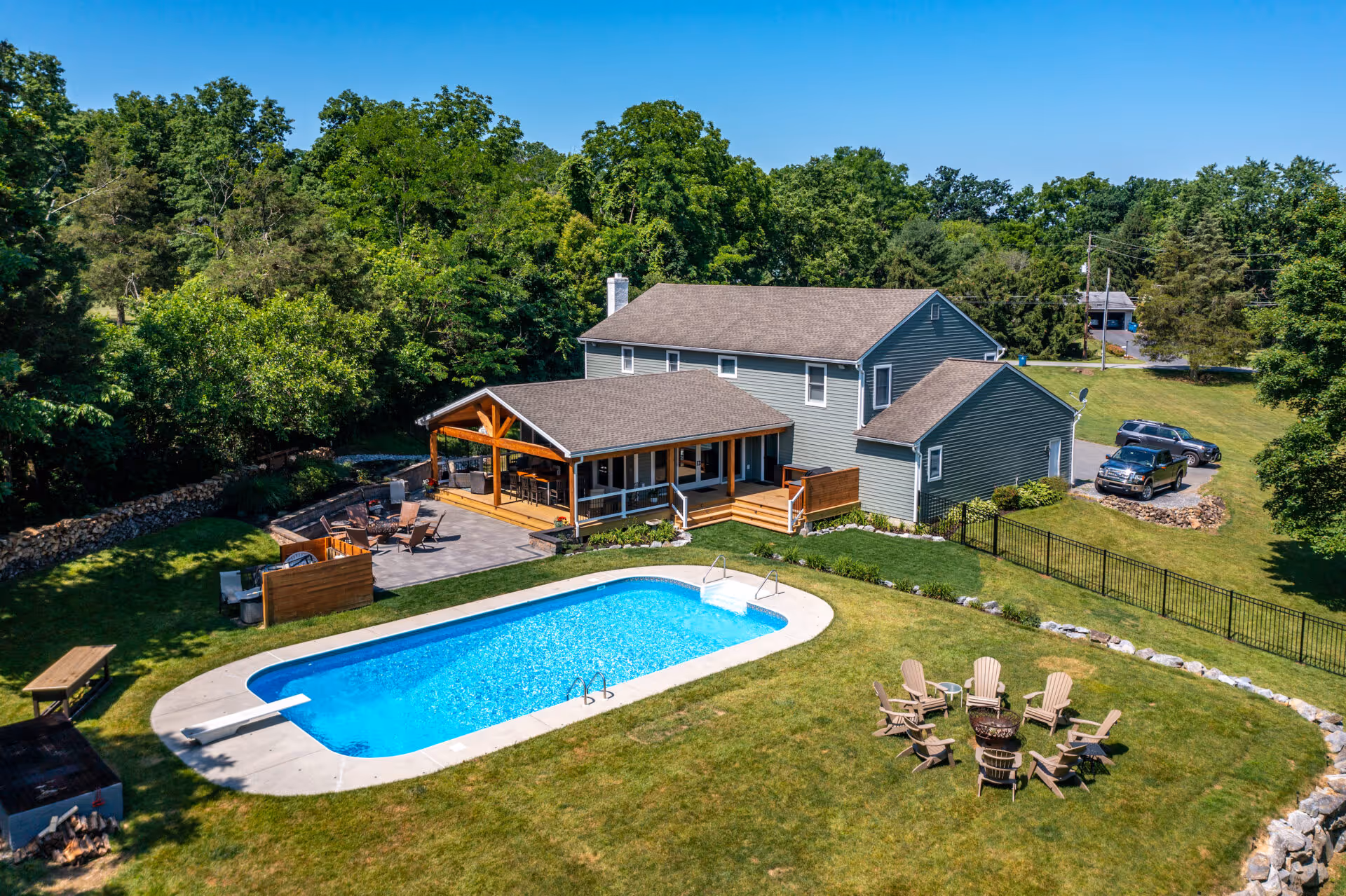 Modern exterior with outdoor pool area, wooden deck, and firepit in Dillsburg, PA