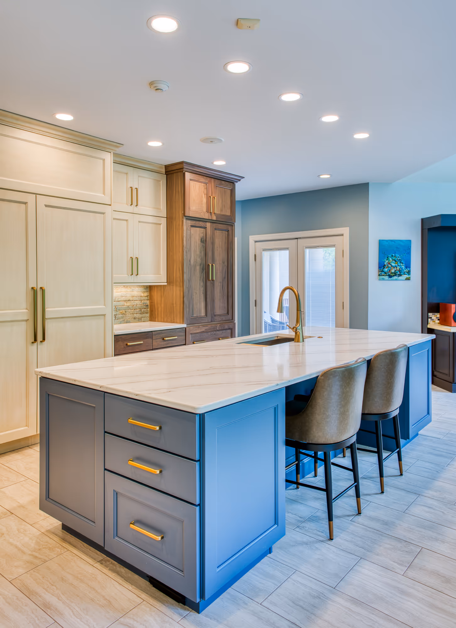 Modern kitchen in Mechanicsburg, PA featuring a blue island, white cabinetry, and marble countertop.
