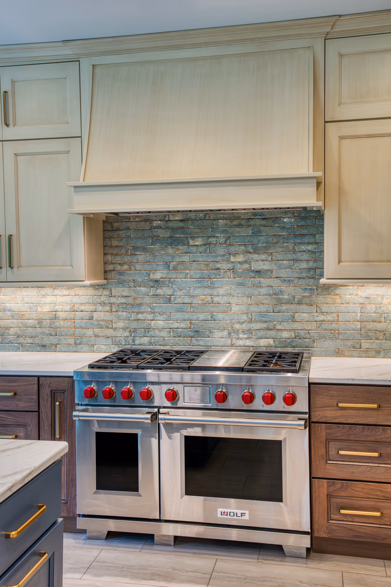 Modern kitchen in Mechanicsburg, PA featuring a Wolf range, stone backsplash, and wooden cabinets.