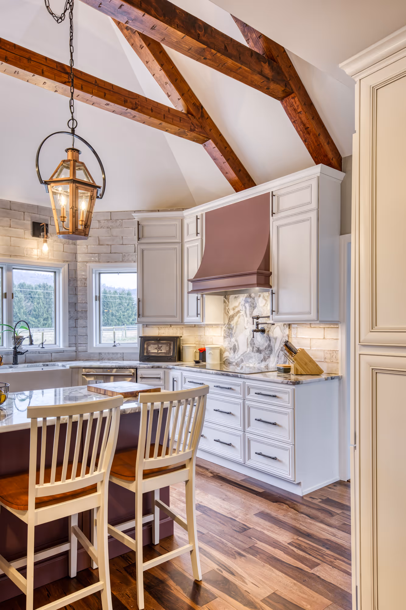 Modern kitchen in enola, pa featuring white cabinetry, a marbled backsplash, wooden beams, and elegant pendant lighting.