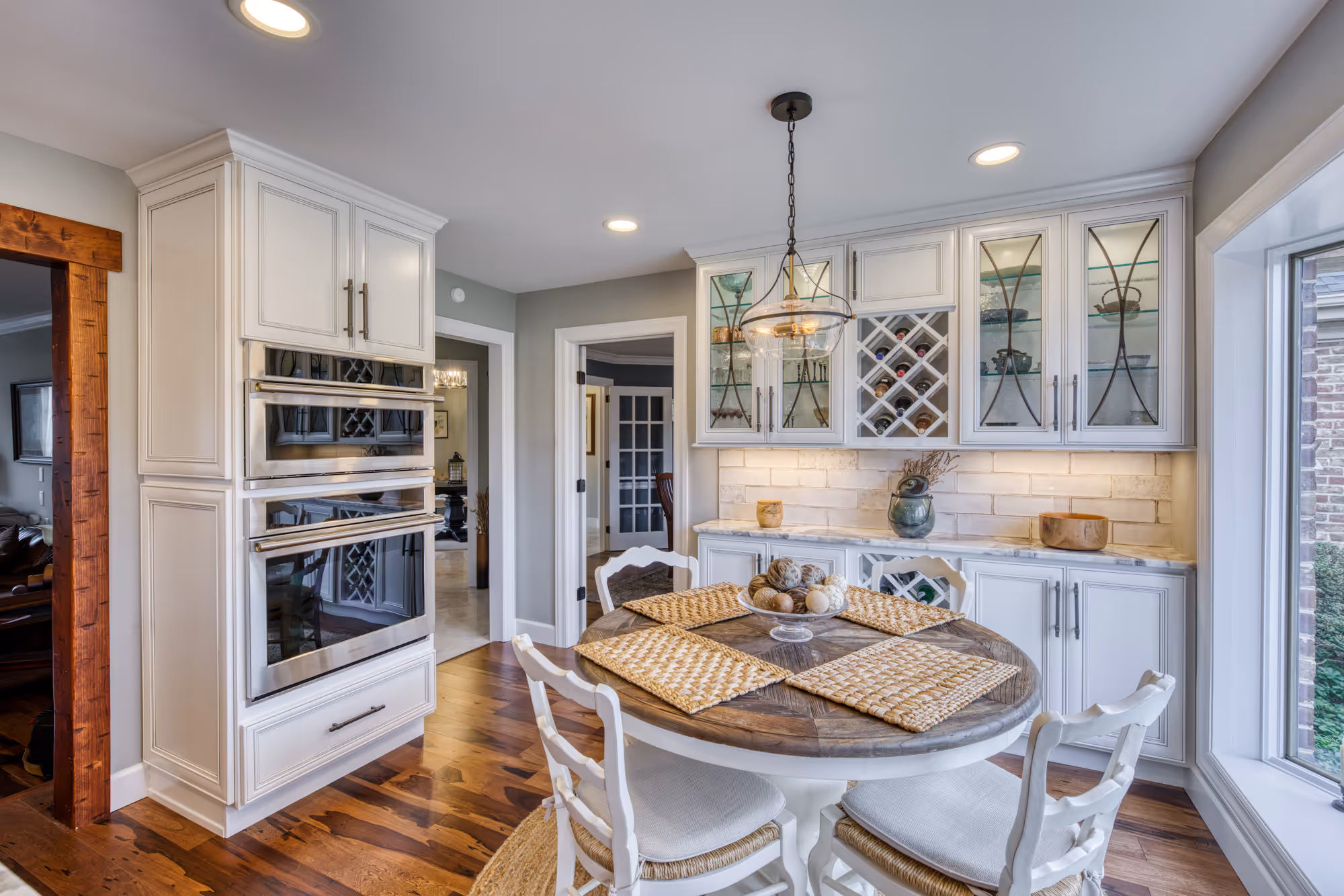 Modern kitchen dining area featuring a round wooden table, white cabinetry, and unique glass-front cabinets in enola, pa