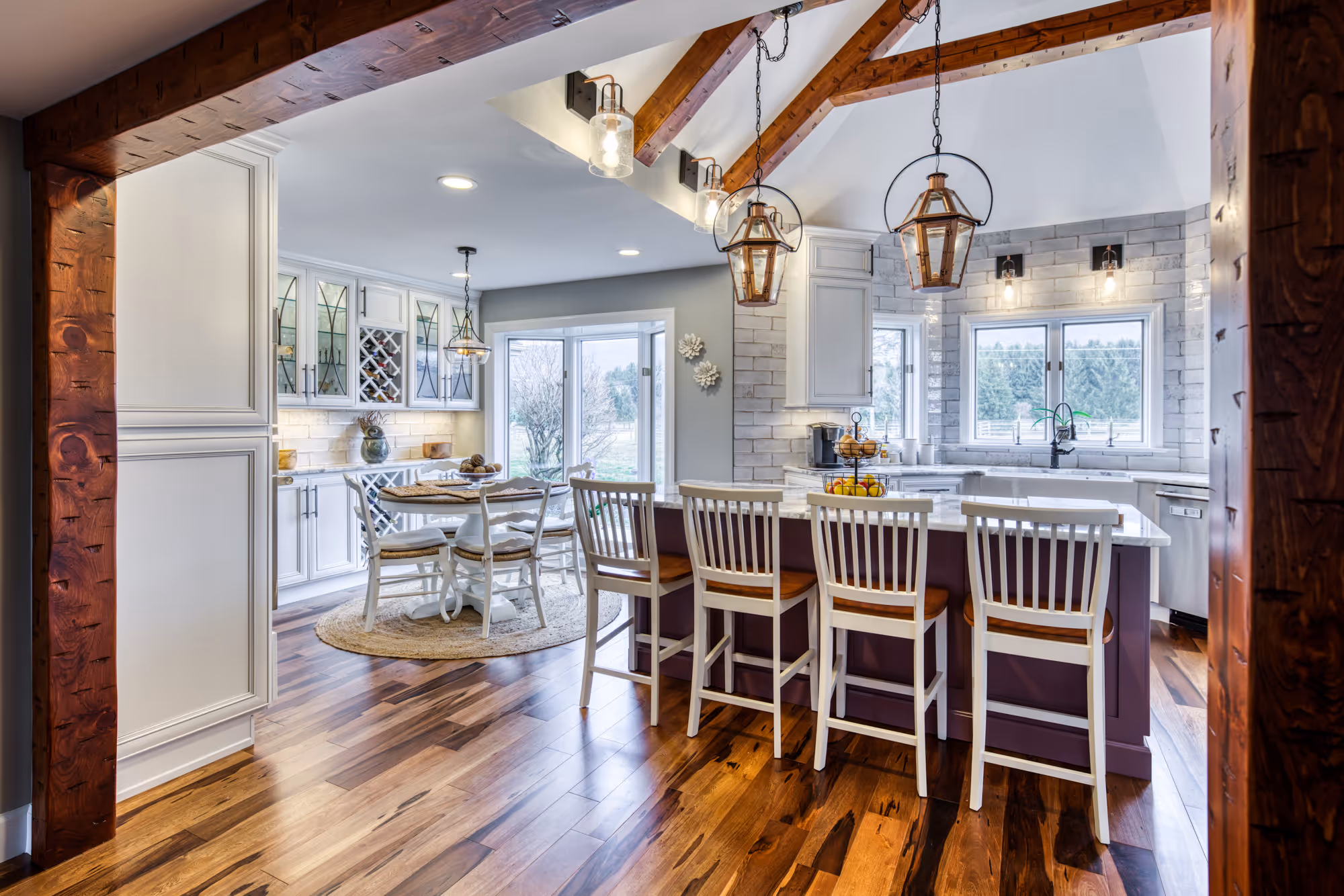 Contemporary kitchen in Enola, PA, featuring wood beams, white cabinets, and spacious layout with a cozy dining area.