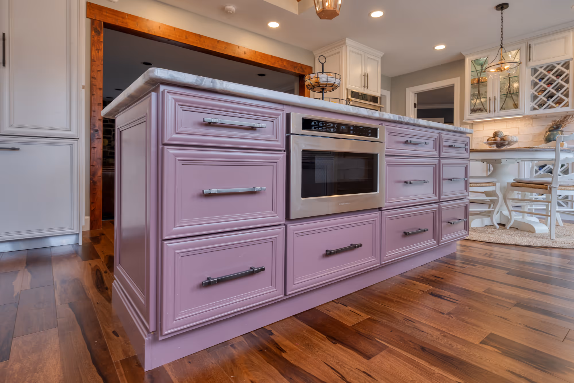 Contemporary kitchen in Enola, PA featuring a pink island with a microwave drawer, modern cabinetry, and wooden flooring.
