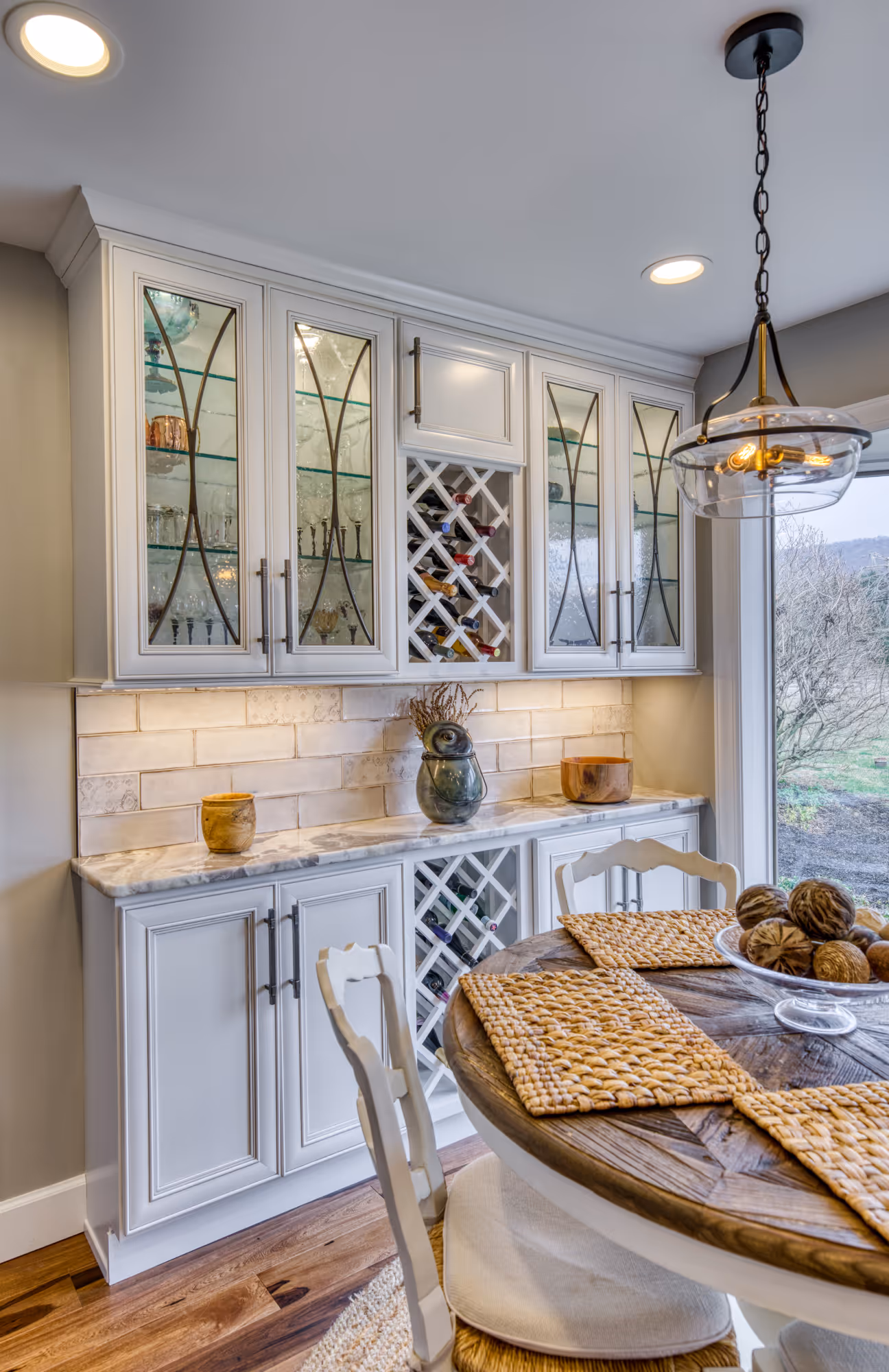 Stylish kitchen remodel in Enola, PA featuring glass door cabinets, marble countertop, woven place mats, and wine storage.
