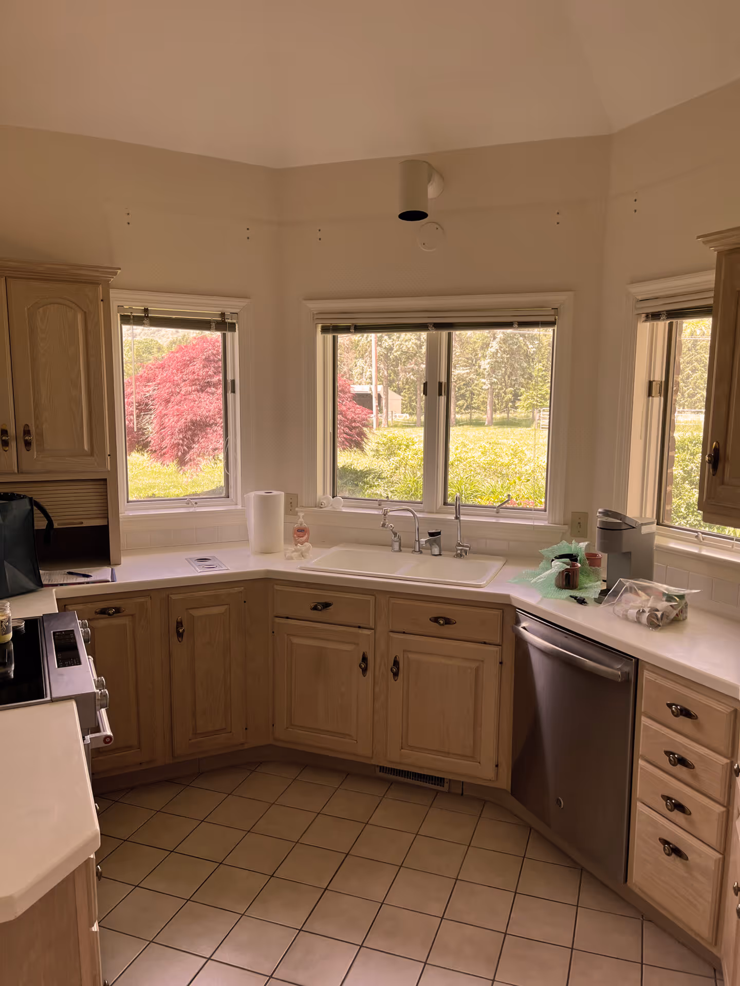 Bright kitchen with light wood cabinets, white countertops, and large windows overlooking greenery in enola, pa.