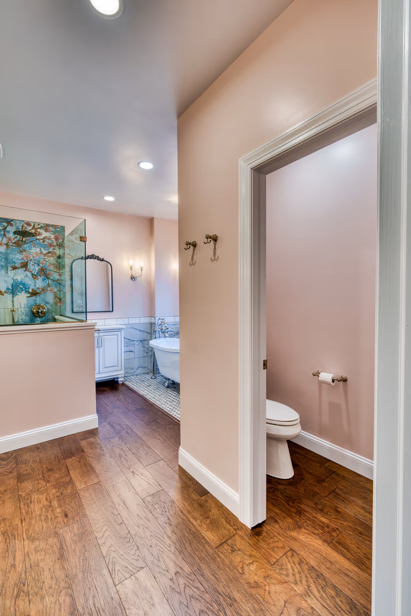 Elegant bathroom in Mechanicsburg, PA with a freestanding tub, wood flooring, and soft pink walls.