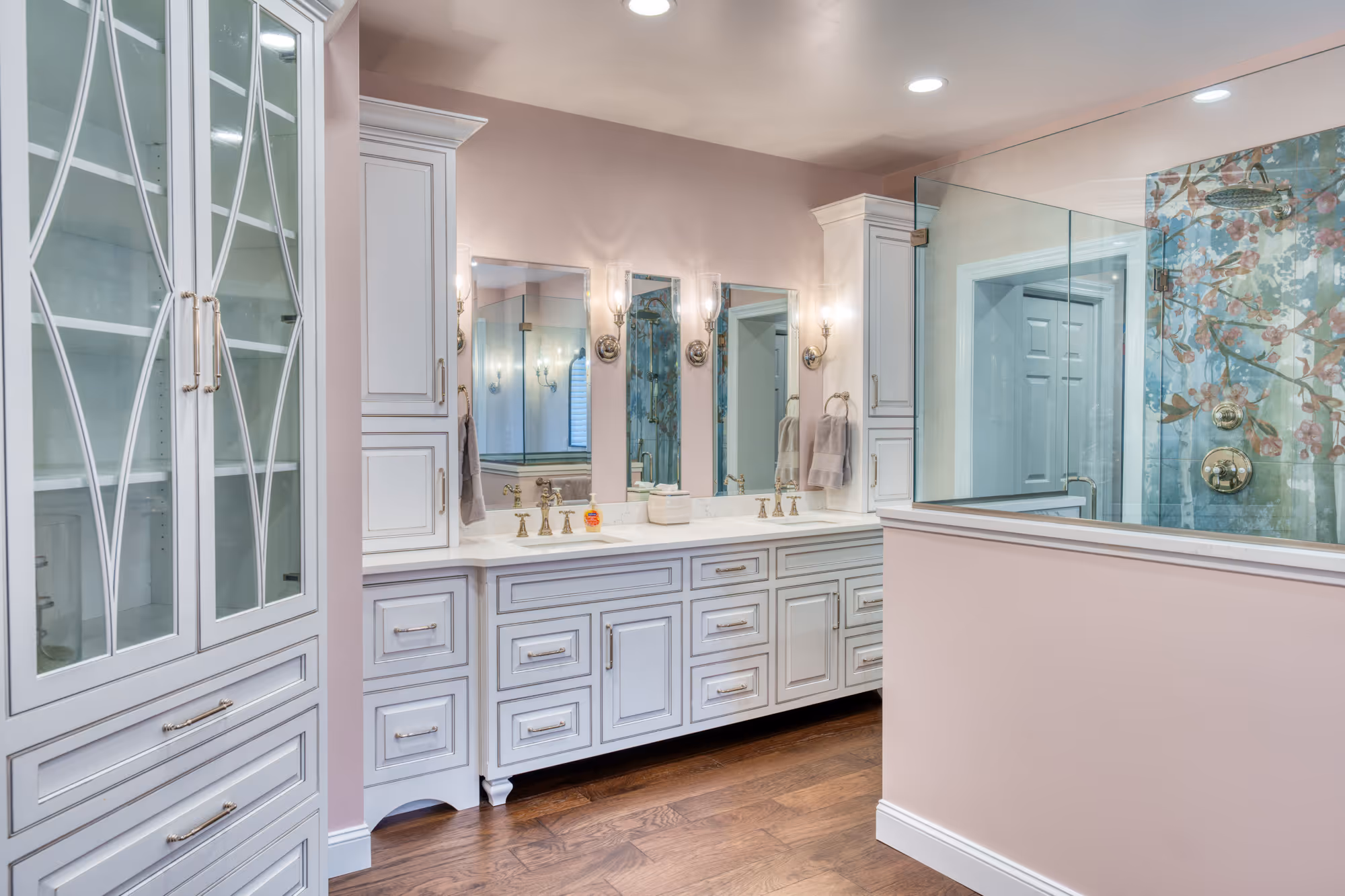 Stylish bathroom in mechanicsburg, pa with pink walls, white cabinetry, and floral glass shower details
