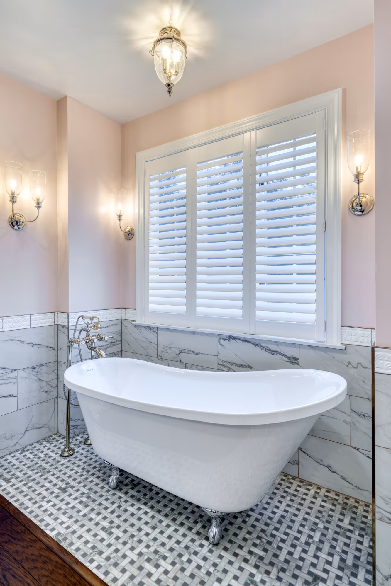 Stylish bathroom in Mechanicsburg, PA, featuring a freestanding tub, marble tile, and modern lighting.